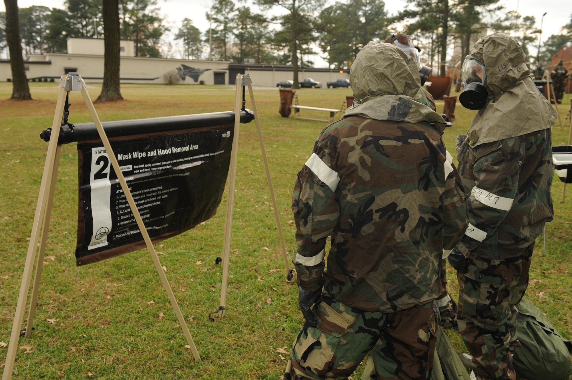 Staff Sgt. Douglas D'Agostino and Airman Joshua Walk, 4th Aircraft Maintenance Squadron, read the mask wipe and hood removal instructions at the contamination control area on Seymour Johnson Air Force Base, N.C., Dec. 7, 2009. The CCA is a four-step process Airmen go through to remove equipment that could have been contaminated. (U.S. Air Force photo/Senior Airman Ciara Wymbs)
