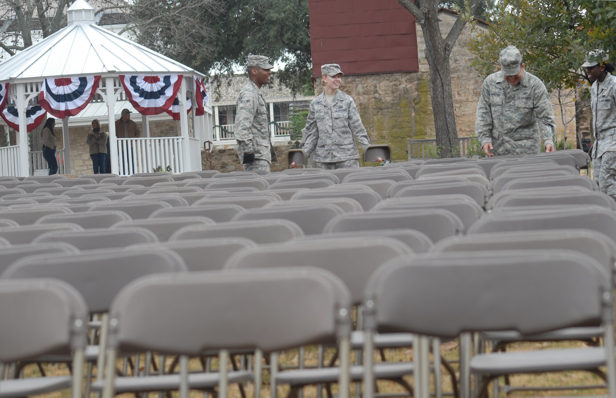 Airman 1st Class Elvin Woodruff, 17th Communications Squadron; Staff Sgt. Brandi Giles, 17th Contracting Squadron; Senior Airman Francisco Manitas, 17th  Comptroller Squadron, and Airman 1st Class Erica Givens, 17th Mission Support Group from Goodfellow AFB, Texas help set up hundreds of chairs for the Pearl Harbor Day remembrance ceremony in Fredericksburg on Dec. 7.  Earlier in the day, they helped set up over 4,000 chairs for the grand opening ceremony of the George H.W. Bush Gallery of the War in the Pacific Museum.  80 volunteers of Soldiers, Sailors, Airman and Marines from Goodfellow travelled 150 miles to help with the opening of the museum expansion, providing chair set-up and tear down, distinguished guests escort and led tours of the new facility.  The former President George H.W. Bush, attended as well as Rick Perry, Governor of Texas.  Over 4,000 people were in attendance.  (U.S. Air Force photo by/Robert D. Martinez)