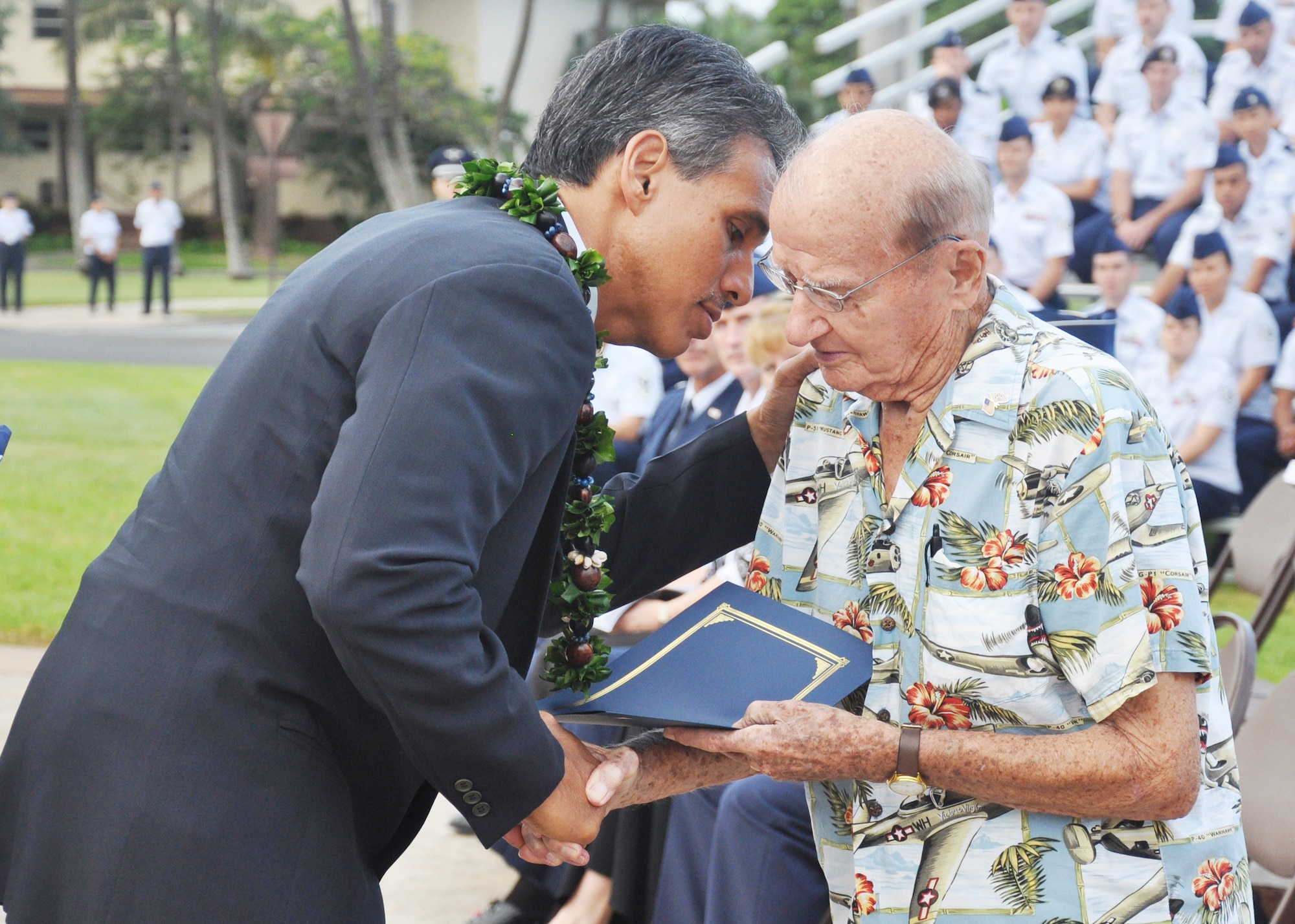 Hawaii Lieutenant Governor James Aiona Jr., pays tribute to retired Col. Andrew Kowalski Dec. 7, 2009, here, during a ceremony that marked the anniversary of the Dec. 7, 1941, attacks on Pearl Harbor Navy Fleet and the Army Air Corps fields of Hickam, Wheeler and Bellows. Survivors and their families from the infamous day were on hand to pay tribute to their lost brothers and sisters in arms. Wreaths and tokens of honor were laid at the base of the memorial at Atterbury Circle. Colonel Kowalski, then a master sergeant, was called to action as a casualty collection officer during the attacks. (U.S. Air Force photo/Staff Sgt. Mike Meares)