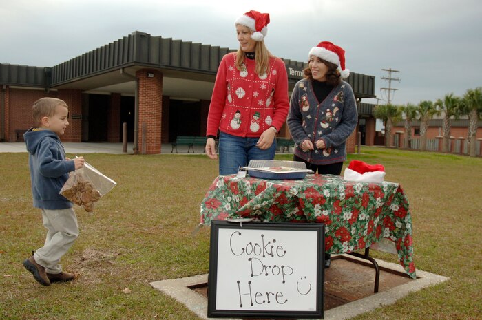 Jackson Neal drops off cookies to Lina Wood, right, and Janet Chapman, left, for the Team Charleston Spouses Club Cookie Drive at the passenger terminal here Dec. 8. The spouse club handed out cookies to Airmen at the Robert D. Gaylor Dining Facility Dec. 8 and will be sending the remaining cookies to the deployed Airmen downrange. Lina is the wife of Col. John Wood, 437th Airlift Wing commander, Janet is the wife of Col. Steven Chapman, 315th Airlift Wing commander, and Jackson is the son of Lt. Col. Robert Neal, 437th Aerial Port Squadron commander. (U.S. Air Force photo/Staff Sgt. Marie Brown)