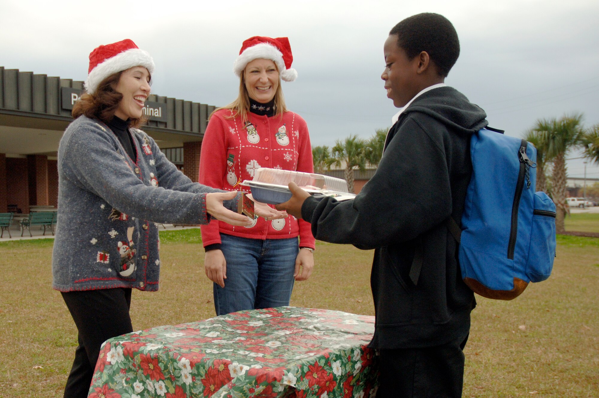 Gary Godley drops off cookies to Lina Wood, left, and Janet Chapman, right, for the Team Charleston Spouses Club Cookie Drive at the passenger terminal here Dec. 8. The spouse club handed out cookies to Airmen at the Robert D. Gaylor Dining Facility Dec. 8 and will be sending the remaining cookies to the deployed Airmen downrange. Lina is the wife of Col. John Wood, 437th Airlift Wing commander, Janet is the wife of Col. Steven Chapman, 315th Airlift Wing commander and Gary is the son of Tech. Sgt. David Godley who is assigned to the 437th Maintenance Operations Squadron. (U.S. Air Force photo/Staff Sgt. Marie Brown)