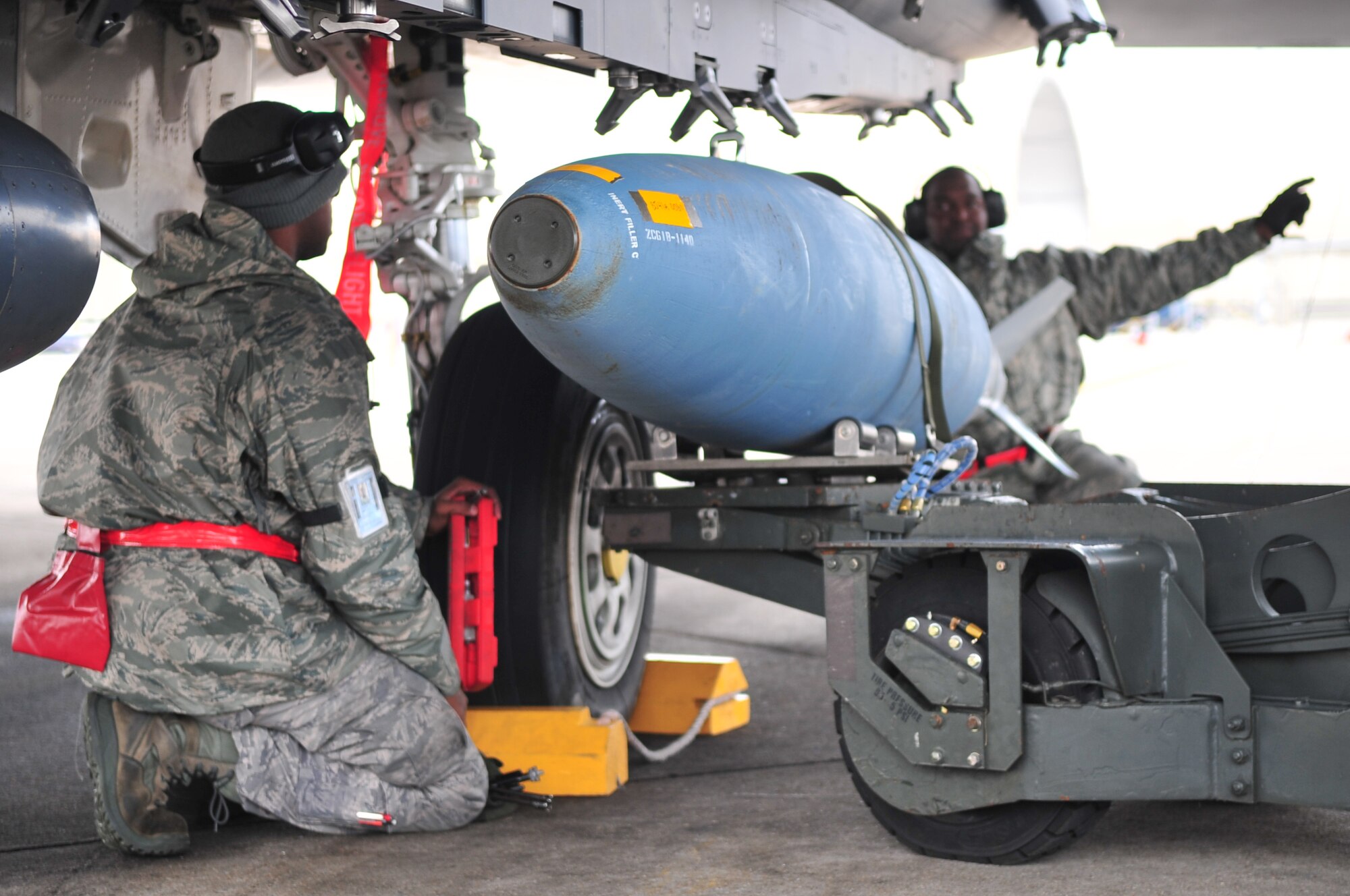 Senior Airman Durrell Hearns, 4th Aircraft Maintenance Squadron weapons crew chief, and Staff Sgt. Rafael Cratch, 4th Aircraft Maintenance Squadron weapons crew chief, guide the weapon loading vehicle under the wing of an F-15E Strike Eagle on Base X, during an operational readiness exercise, Dec. 8, 2009. The weapons loading vehicle, or jammer, can raise, lower and rotate the munitions to load it onto the jet. During the week-long exercise, Airmen will test their ability to execute wartime taskings, generate combat sorties under simulated wartime conditions and provide combat airpower in the region. (U.S. Air Force photo/Airman 1st Class Rae Perry)