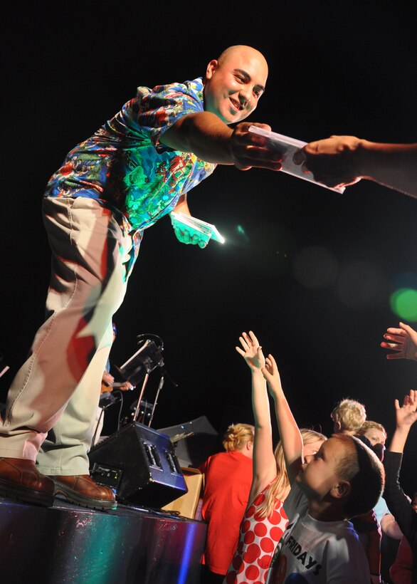 HICKAM AIR FORCE BASE, Hawaii -- Staff Sgt. Richard Vasquez, a vocalist with Hana Hou, U.S. Air Force Band of the Pacific - Hawaii, hands out holiday music recorded by the Band of the Pacific during a performance Dec. 4 at the Freedom Tower Lighting celebration. More than 5,000 multi-colored twinkle lights make the tower Oahu's largest Christmas tree at 171 feet tall. This year marked the 40th anniversary of the freedom tower lighting. Hickam's history reports that it was spared from the Japanese attack on Dec. 7, 1941 because they believed the majestic tower was our place of worship. The tower stored 500,000 gallons of emergency water for the base. (U.S. Air Force photo/Staff Sgt. Mike Meares)