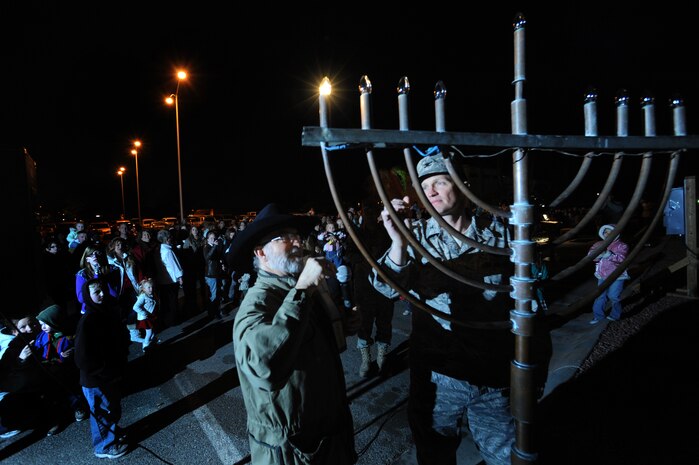 NELLIS AIR FORCE BASE, Nev. - Col. Dave Belote 99th Air Base Wing, commander and Rabbi, Shmuel Oppenheim light the Menorah during Nellis's annual Menorah and Christmas tree lighting ceremony at the Base Chapel Dec. 4.  Airman and their Families  gathered outside the chapel to sing Christmas carols, meet Santa Claus, and celebrate the holiday season. (U.S. Air Force photo by Tech. Sgt. Michael R. Holzworth)