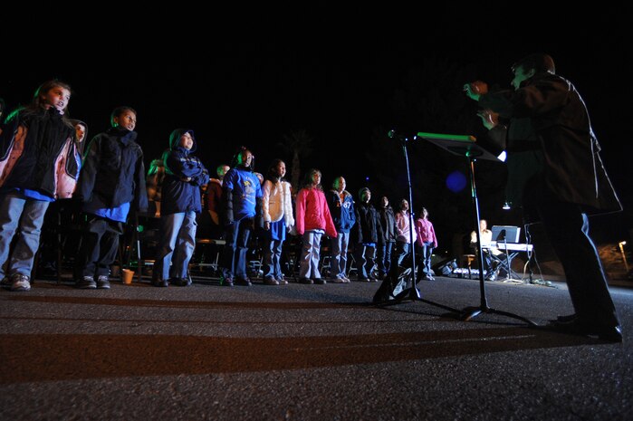 NELLIS AIR FORCE BASE, Nev. - Ms. Carolyn Peterson conducts the Lomie Heard Chorus during Nellis's annual Menorah and Christmas tree lighting ceremony at the Base Chapel Dec. 4.  Airman and their Families  gathered outside the chapel to sing Christmas carols, meet Santa Claus, and celebrate the holiday season.(U.S. Air Force photo by Tech. Sgt. Michael R. Holzworth)