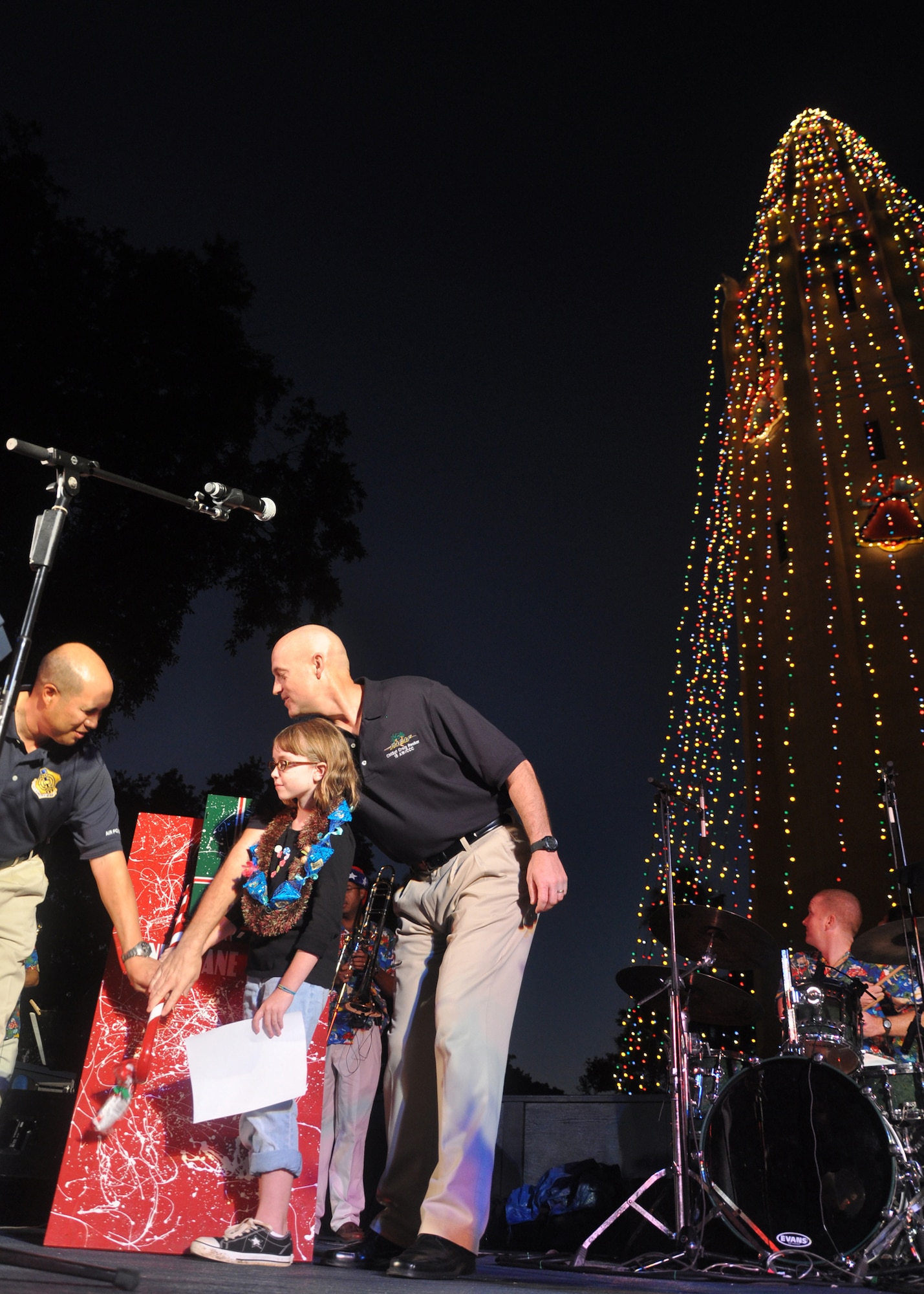 HICKAM AIR FORCE BASE, Hawaii -- Col. Giovanni Tuck, 15th Airlift Wing commander, Emily O'Malley, 9, the daughter of Maj. Scott O'Malley, Pacific Air Forces Headquarters, and wife Angela, and Chief Master Sgt. Craig Recker, 15th AW command chief master sergeant, throw the "candy cane switch" on the Freedom Tower lights during the 40th anniversary of the tower lighting. More than 5,000 multi-colored twinkle lights make the tower Oahu's largest Christmas tree. (U.S. Air Force photo/Staff Sgt. Mike Meares)
