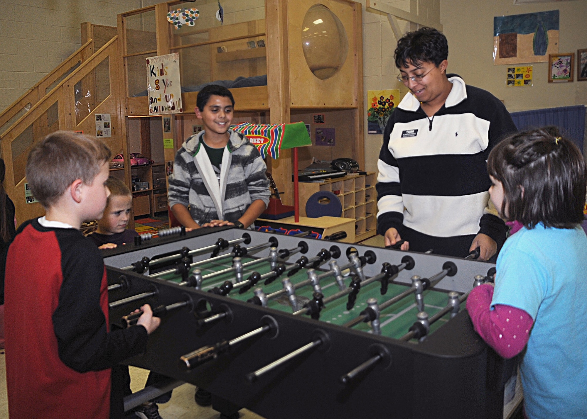 CANNON AIR FORCE BASE, N.M.-- Monique Hyman,School Age Program manager here, plays foosball with the kids Dec. 2 at the Cannon's Youth Center.The school program received five-star accreditation by the National Afterschool Association.   (U.S. Air Force photo by Airman 1st Class Maynelinne De La Cruz) 