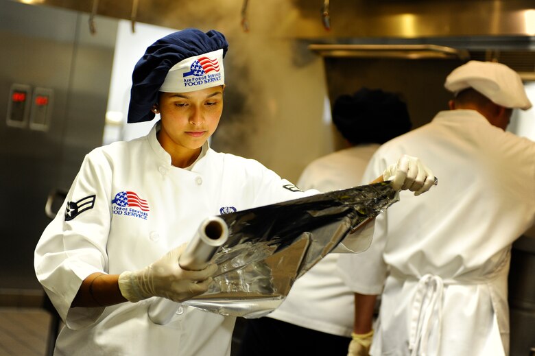 Airman 1st Class Nadia Amaya, 1st Special Operations Force Support Squadron food service specialist, unrolls tin foil to cover her vegetable dish during the quarterly Top Chef competition Dec. 3 at Hurlburt Field. (Air Force photo by Senior Airman Julianne Showalter)