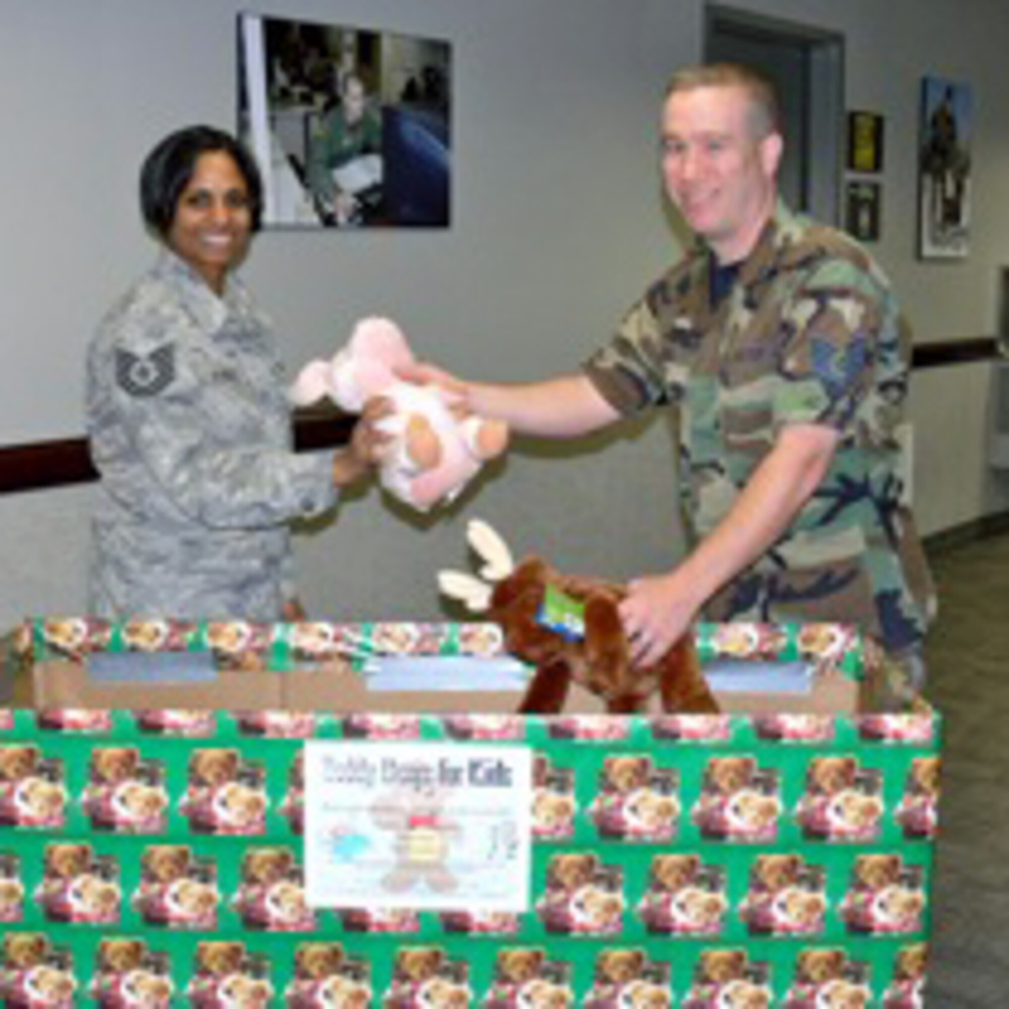 Tech. Sgt. Tanisha Hunter, 21st Space Wing command section, gives Tech. Sgt. Thom Moore, 21st SW ground safety technician, a stuffed animal for a holiday Teddy Bears for Kids drive. The collected Teddy bears will be delivered Dec. 22 to children in the pediatric ward of Penrose St. Francis Medical Center. The drive continues through Dec. 11. Teddy bears can be dropped off in the Safety office, Building 845, room 107, or at Child Care Connections, 125 N. Parkside, Suite 202, Colorado Springs. (Air Force photo by Monica Mendoza)