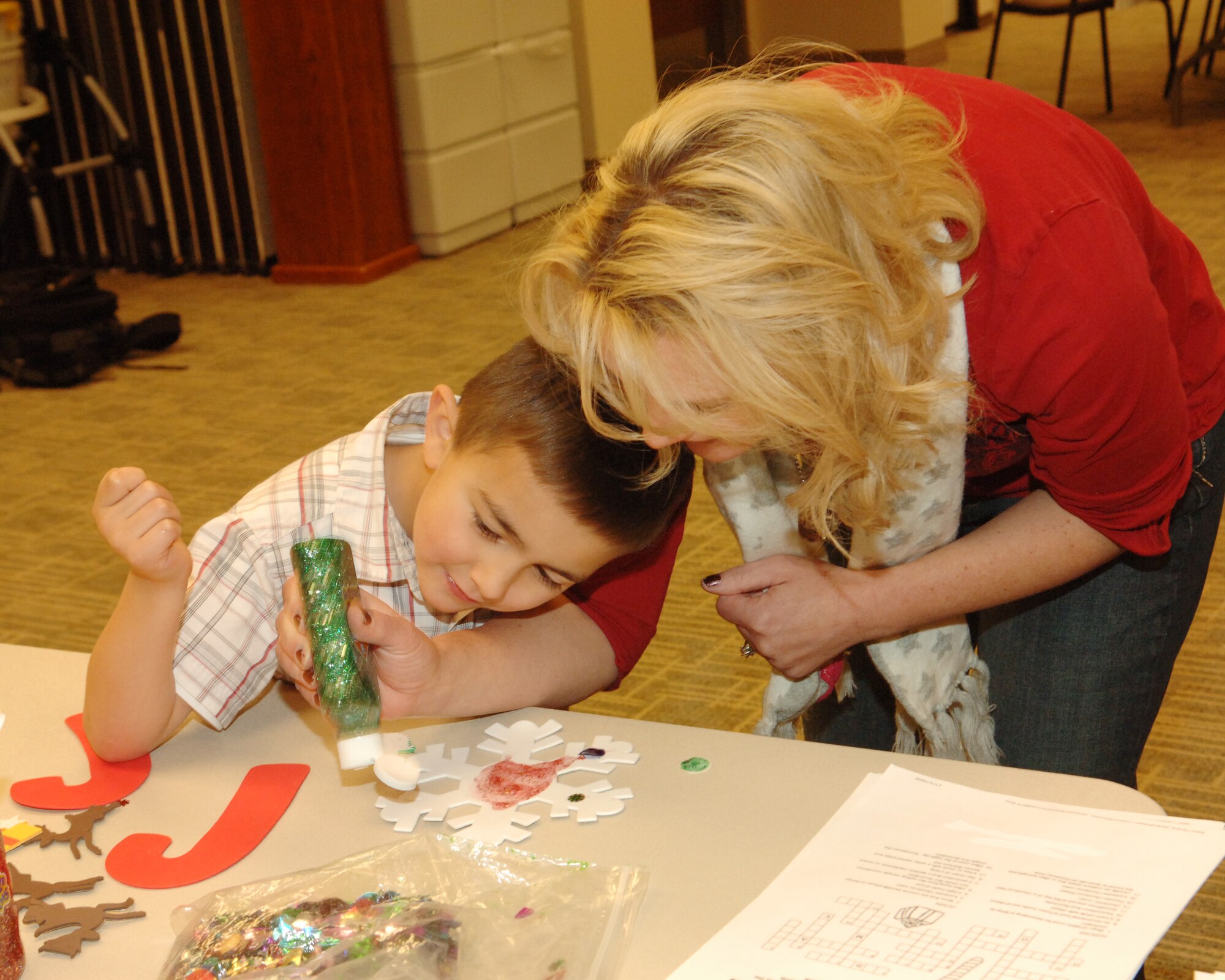 BUCKLEY AIR FORCE BASE, Colo. -- Gidget Barela shows her son Chance how to apply glue glitter to a snowflake during the Deployed Spouses Family Dinner at the Chapel Annex Dec. 4. (U.S. Air Force photo by Tech. Sgt. Shirley Henderson)