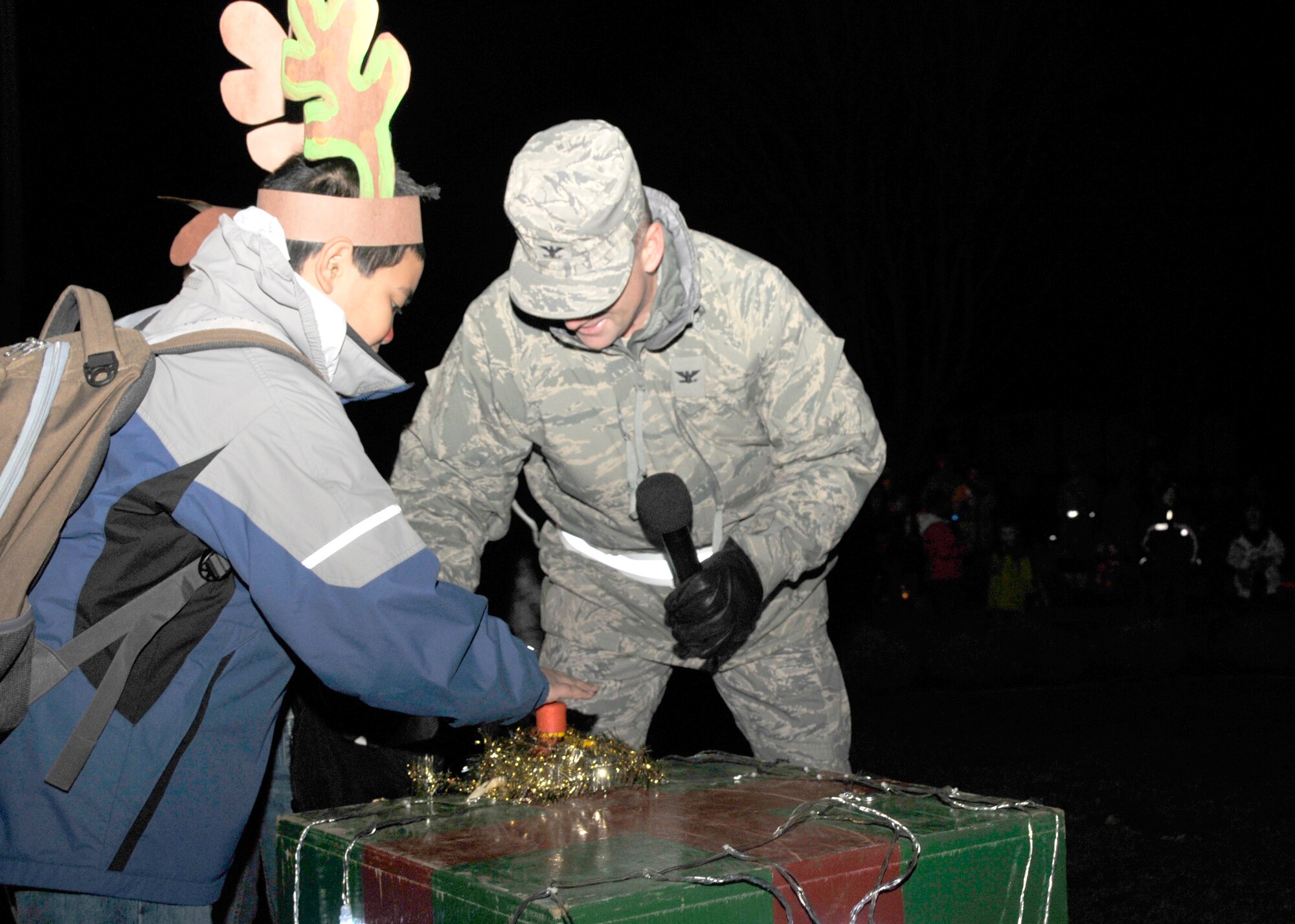 Col. Jay Silveria, 48th Fighter Wing commander, assisted by Tyler Cruz, son of Tech. Sgts. Nanette Cruz, 48th Medical Support Squadron Systems Flight NCO in charge, and Anthony Cruz, 48th Medical Support Squadron Laboratory technician, press the lever that turned on the lights at the annual Christmas tree lighting ceremony held on RAF Lakenheath, England, Dec. 4.  The ceremony signified the start of the Christmas season.   (U.S. Air Force photo by Airman 1st Class Eboni Knox)