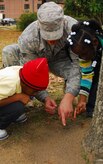 Senior Airman Alexander Jones points out a mound of fire ants to Donald Vanderhorst, left, and Danaija Duncan, right, during a picnic outside the Airman Leadership School here Dec. 4. The two children were joined by fellow third grade classmates for a tour of Charleston AFB held annually as a mentorship program to reach out to children in the local community. Airman Alexander is a student enrolled in ALS. (U.S. Air Force photo/Staff Sgt. Daniel Bowles)