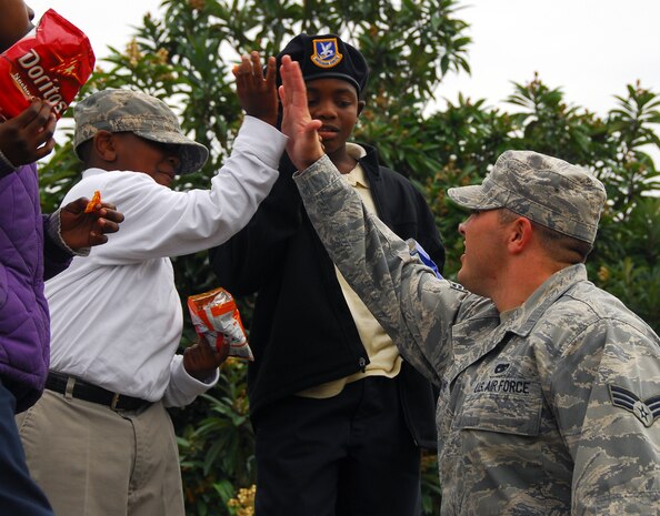Senior Airman Alexander Jones gives Kamal Canty a high-five during a picnic outside the Airman Leadership School here Dec. 4. Kamal and his classmate Shane White, center, visited Charleston AFB with fellow students from Memminger Elementary School for a base tour hosted by their mentors enrolled in ALS. Airman Jones is an ALS student assigned to the 437th Aerial Port Squadron. (U.S. Air Force photo/Staff Sgt. Daniel Bowles)