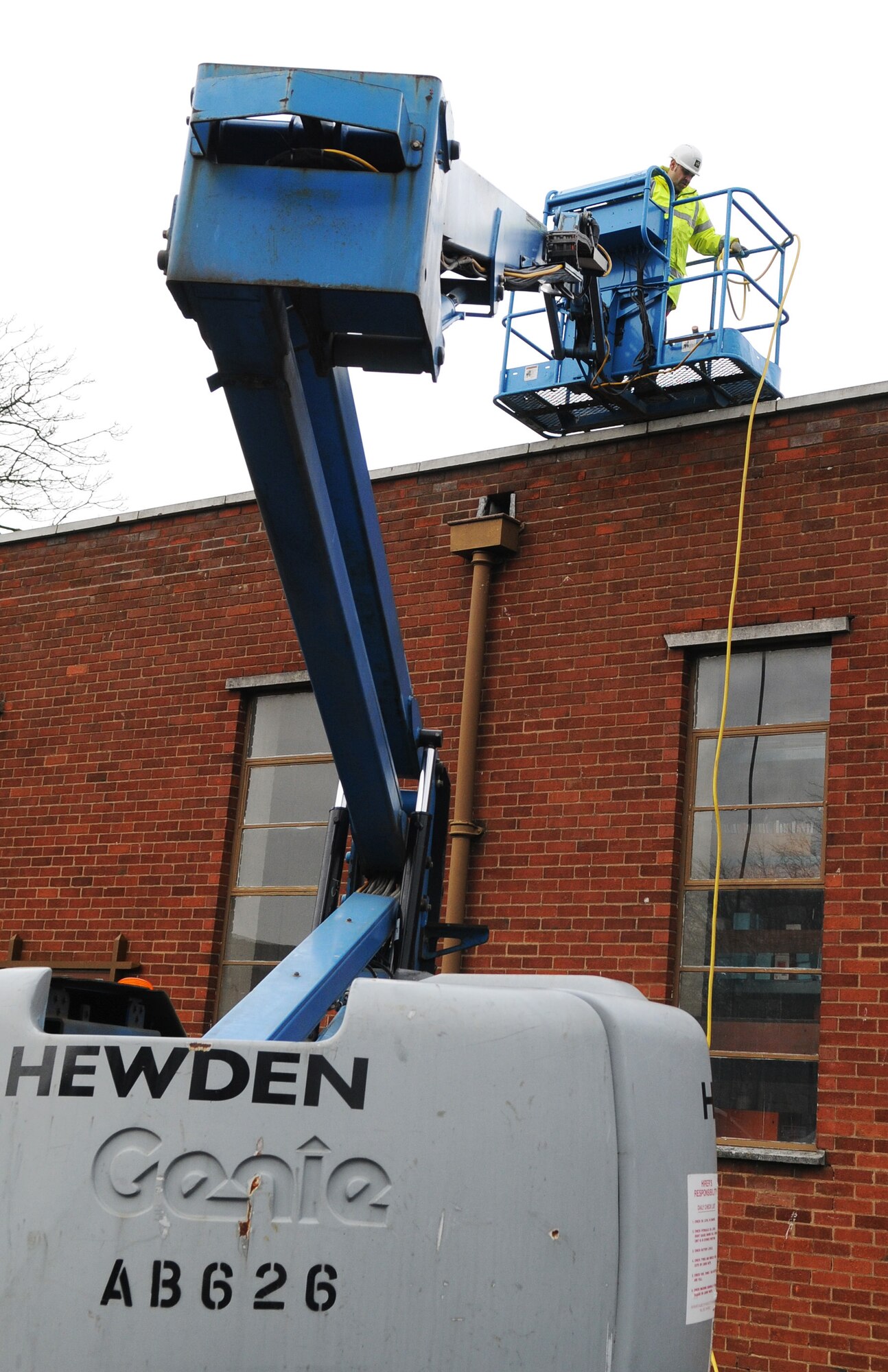 RAF MILDENHALL, England -- John Milton, a local contractor, uses an articulating boom to check the roof of the Auto Skills Development Center for leaks and ensure the safety of mechanics inside. A facility worker was worried that rain water was leaking into the shop and posing a safety hazard, so contractors were called to examine the seals around the roof vents. The articulating lift provides up, out and over positioning abilities for working in hard to reach areas. (U.S. Air Force photo/Senior Airman Thomas Trower) 