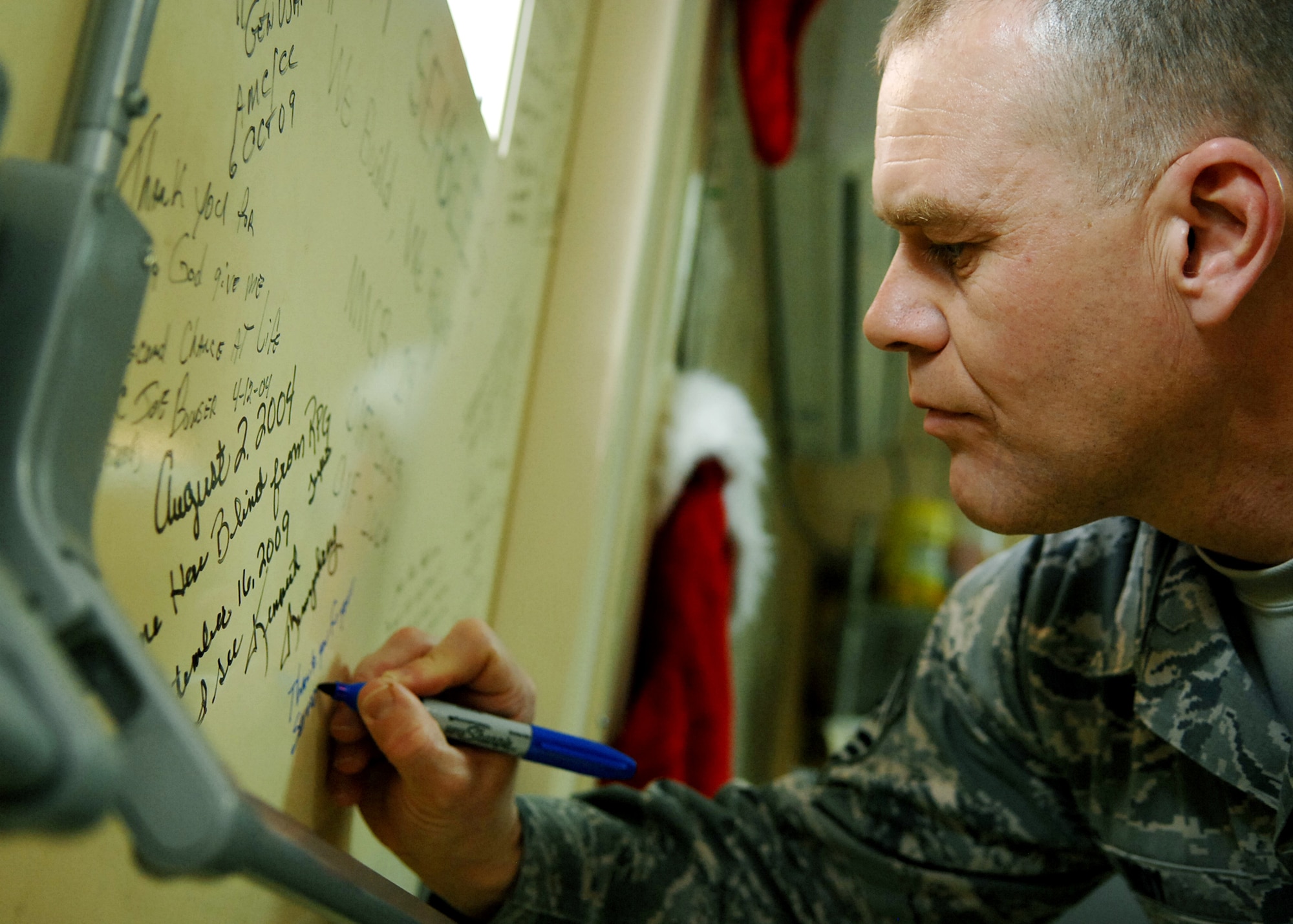 JOINT BASE BALAD, Iraq -- Chief Master Sgt. of the Air Force James Roy signs the warrior wall at the Air Force Theater Hospital Dec. 4, 2009. During his first visit to Joint Base Balad as the chief master sergeant of the Air Force, Chief Roy toured various locations on the base and mentored Airmen during an Airman's call. (U.S. Air Force photo/Senior Airman Christopher Hubenthal)