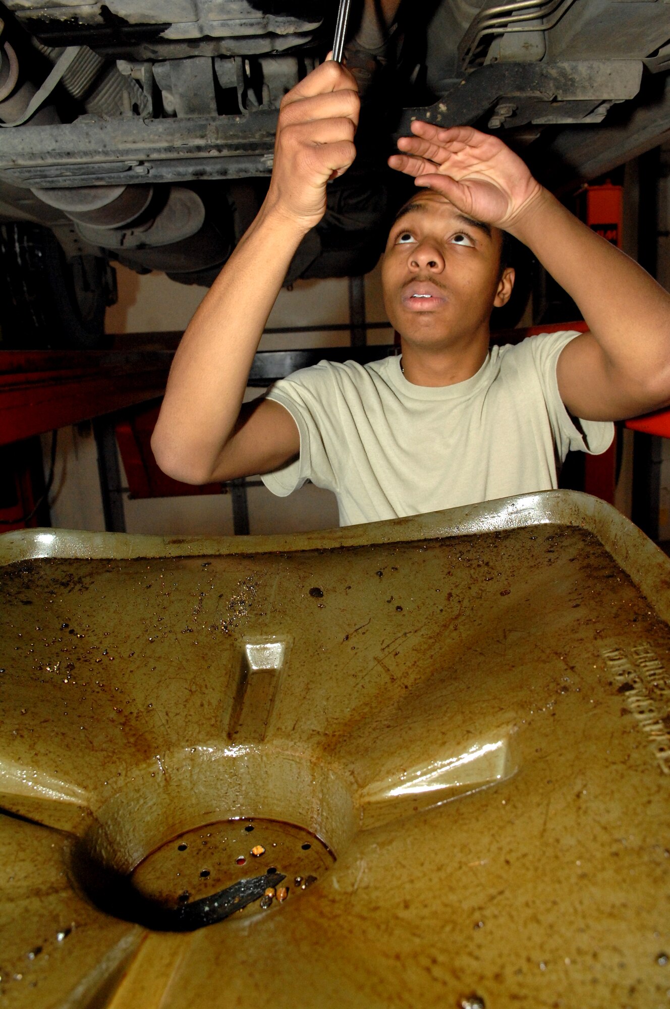MINOT AIR FORCE BASE, N.D. -- Airman 1st Class Aaron-Forrest Wainwright, 5th Bomb Wing public affairs photographer, changes his oil at the auto hobby shop here Dec. 2. The use of on-base facilities such as this helps all Minot AFB Airmen hone their automotive skills. (U.S. Air Force photo by Senior Airman Michael Veloz)