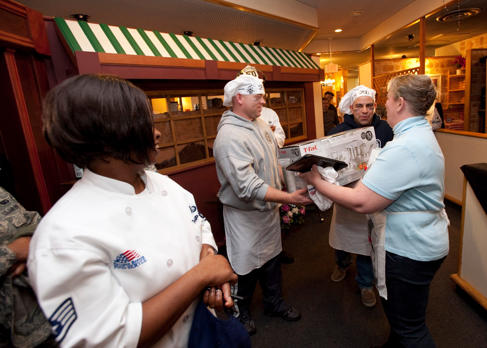 MISAWA AIR BASE, Japan -- Erin Robinson, 35th Force Support Squadron night operations manager and A-Team chef, presents the firefighters of Team Diversity with a cookware set at the conclusion of Grissom Dining Facility's Iron Chef competition. The A-Team won the competition, but in a show of good sportsmanship, Mrs. Robinson gave her winnings -- the cookware set -- to the runner-ups. (U.S. Air Force photo/Staff Sgt. Samuel Morse)