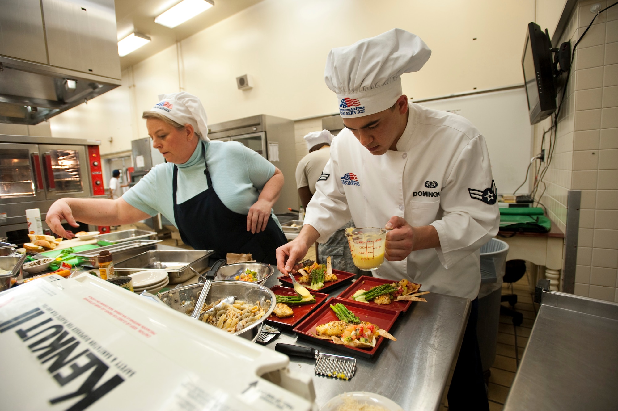 MISAWA AIR BASE, Japan -- Airman 1st Class Frank Dominguez, 35th Force Support Squadron food service journeyman and sous-chef for the A-Team, pours hollandaise sauce over asparagus during Grissom Dining Facility's Iron Chef competition Dec. 4. The featured ingredient for the competition was egg, which required the teams to make egg part of every dish. (U.S. Air Force photo/Staff Sgt. Samuel Morse)