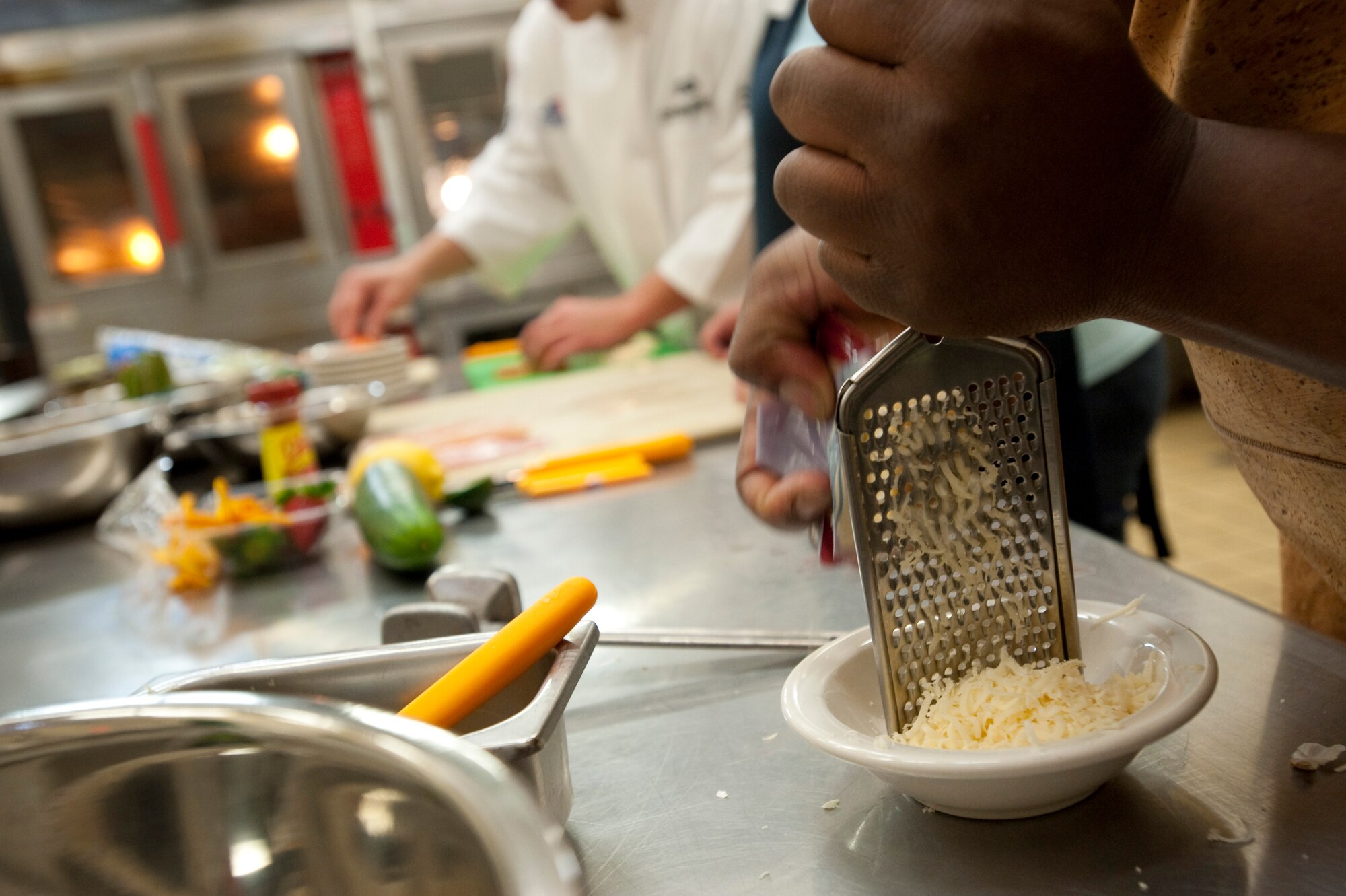 MISAWA AIR BASE, Japan -- Staff Sgt. Michael Venson, 35th Aircraft Maintenance Squadron avionics technician, grates parmesan cheese during the Iron Chef Competition at Grissom Dining Facility Dec. 4. Sergeant Venson brought his own recipe for pasta salad to the competition. (U.S. Air Force photo/Staff Sgt. Samuel Morse)