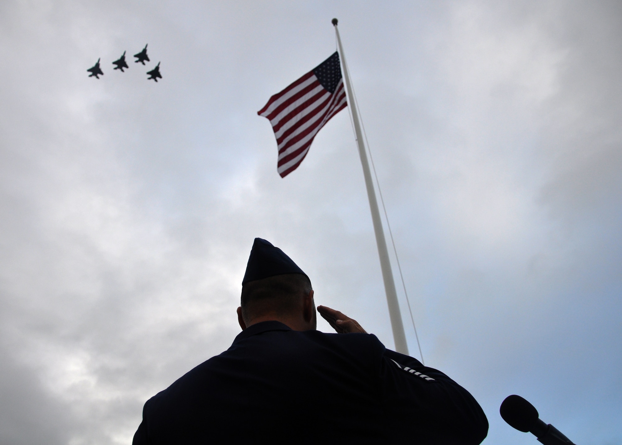 HICKAM AIR FORCE BASE, Hawaii -- Master Sgt. John Sieh, 15th Airlift Wing protocol office, salutes the flag as the 199th Fighter Squadron, Hawaii Air National Guard, F-15s fly a missing man formation during the 68th Remembrance Ceremony Dec. 7, 2009. The ceremony marked the anniversary of the Dec. 7, 1941, attacks on Pearl Harbor Navy Fleet and the Army Air Corps fields of Hickam, Wheeler and Bellows. Wreaths and tokens of honor were laid at the base of the memorial at Atterbury Circle. (U.S. Air Force photo/Staff Sgt. Mike Meares)