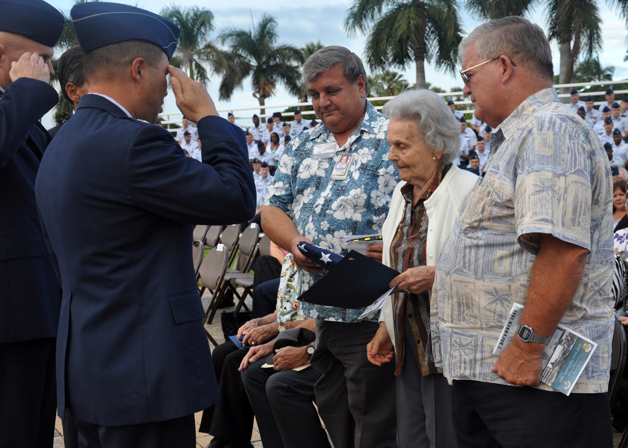 HICKAM AIR FORCE BASE, Hawaii -- Col. Giovanni Tuck, 15th Airlift Wing commander, salutes the flag presented to Helen Burnett, the widow of Col. (Ret.) Vane Ward Burnett, during the 68th Remembrance Ceremony Dec. 7. The remembrance ceremony marked the anniversary of the Dec. 7, 1941, attacks on Pearl Harbor Navy Fleet and the Army Air Corps fields of Hickam, Wheeler and Bellows. Survivors and their families from the infamous day were on hand to pay tribute to their lost brothers and sisters in arms. Wreaths and tokens of honor were laid at the base of the memorial at Atterbury Circle. Colonel Burnett, who passed away two weeks prior to the ceremony, watched as Japanese planes attacked Pearl Harbor and Hickam Field. (U.S. Air Force photo/Staff Sgt. Mike Meares)