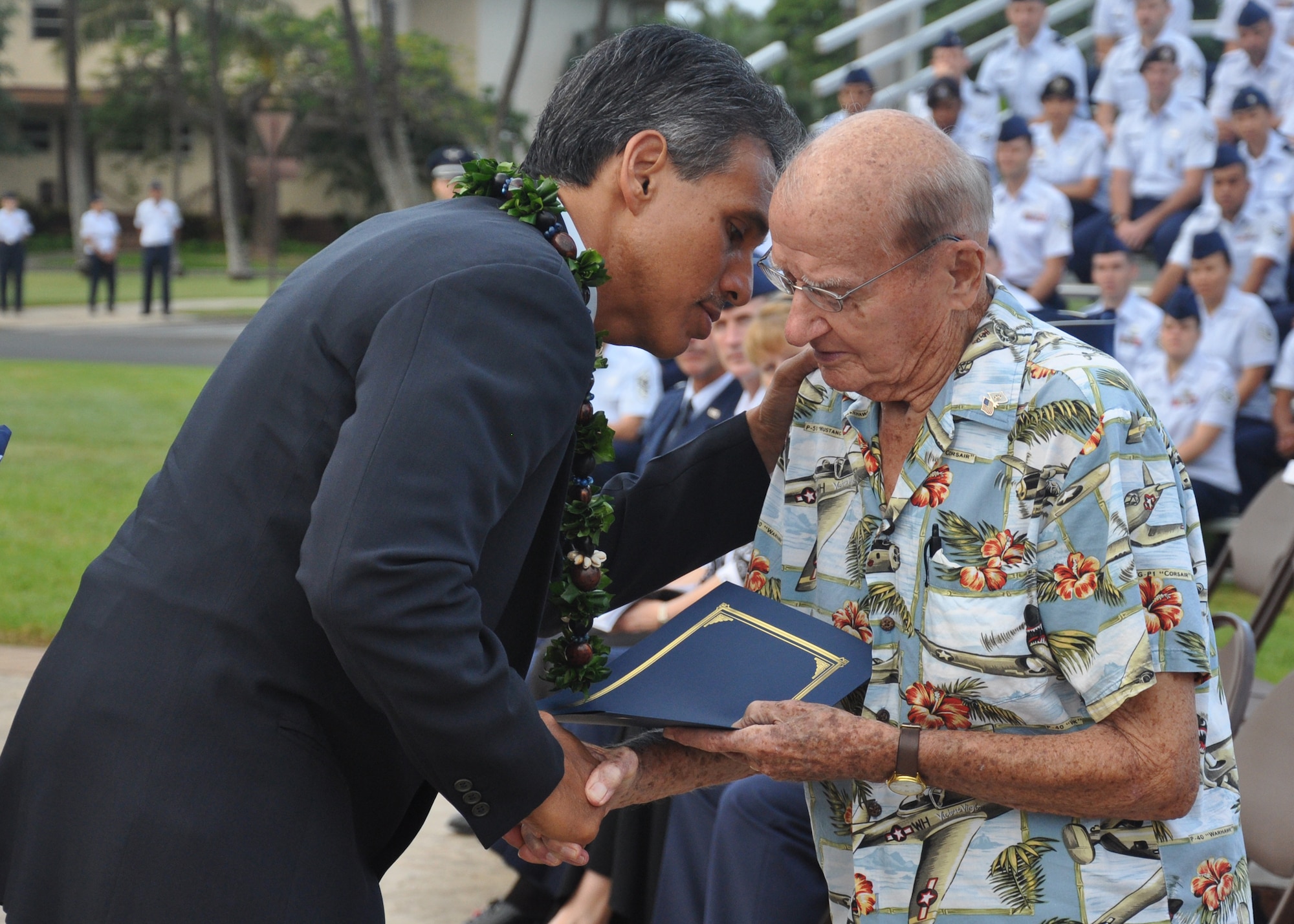 HICKAM AIR FORCE BASE, Hawaii -- Hawaii Lieutenant Governor James ?Duke? Aiona, Jr., pays tribute to U.S. Air Force Col. (Ret.) Andrew Kowalski during the ceremony that marked the anniversary of the Dec. 7, 1941, attacks on Pearl Harbor Navy Fleet and the Army Air Corps fields of Hickam, Wheeler and Bellows. Survivors and their families from the infamous day were on hand to pay tribute to their lost brothers and sisters in arms. Wreaths and tokens of honor were laid at the base of the memorial at Atterbury Circle. Colonel Kowalski, then a master sergeant, was called to action as a casualty collection officer during the attacks. (U.S. Air Force photo/Staff Sgt. Mike Meares)