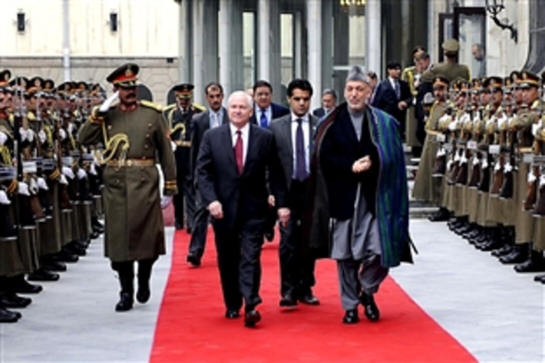 U.S. Defense Secretary Robert M. Gates walks with Afghan President Hamid Karzai at the presidential palace in Kabul, Dec. 8, 2009. Gates is on his first trip to Southwest Asia following President Barack Obama's decision to send an additional 30,000 troops to Afghanistan. 