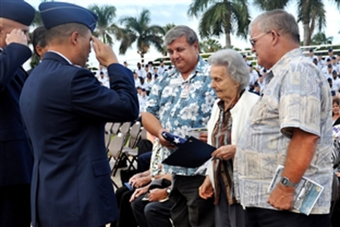U.S. Air Force Col. Giovanni Tuck salutes the flag presented to Helen Burnett, the widow of retired Col. Vane Ward Burnett, during the 68th Remembrance Ceremony on Hickam Air Force Base, Hawaii, Dec. 7, 2009. The ceremony marked the Dec. 7, 1941, attacks on Pearl Harbor Navy Fleet and the Army Air Corps fields of Hickam, Wheeler and Bellows.