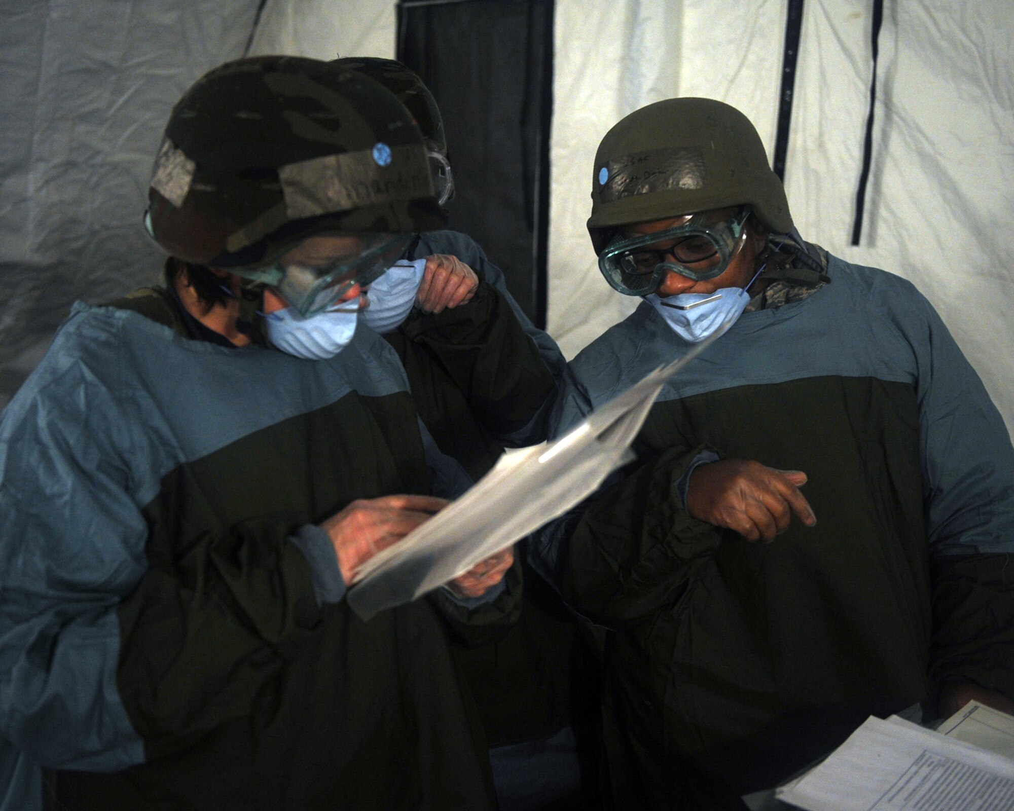 Airmen from mortuary affairs look over a convoy list at tent city on Base X during a Phase II operational readiness exercise, Dec. 8, 2009. A convoy list is an accountability log that tracks the movements of bodies of the deceased from pick up to final destination, including any stops en route. The exercise requires Airmen to wear chemical gear, conduct self-aid and buddy care, take cover during attacks, and offers realistic scenarios to enhance the flying skills of air crew from the 4th Fighter Wing. (U.S. Air Force photo/Senior Airman Ciara Wymbs)