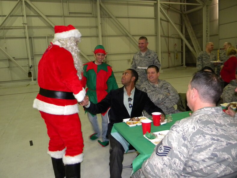 Santa (Tech. Sgt. Bryan Kotcher, age mechanic) and his elf (Senior Airman Sasha Ghazarian, avionics technician) greet Aaron Goodly, administrative assistant, at the 13th Reconnaissance Squadron’s holiday celebration, Dec 6.  Dock 6 was decked for the occasion, and the holiday spread included tri-tip grilled by the squadron's volunteer chefs.  13th RS members and their families also enjoyed children’s activities and Santa gifts. The 13th RS is part of the 940th Wing, Beale Air Force Base, Calif.  (U.S. Air Force photo/Tech. Sgt. Kenneth McCann)