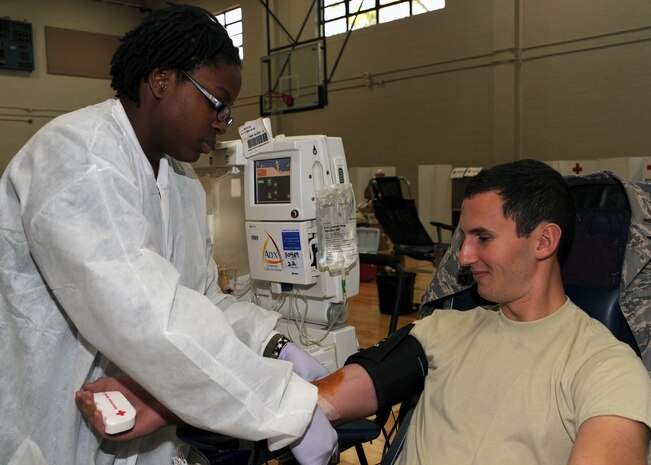 Joelle Parlor secures the needle in 2nd Lt. Lyndon Bartlett's arm to take blood at the Fitness and Sports Center here Dec. 8. The American Red Cross Charleston Service Center comes to the base every 56 days to give members of Team Charleston a chance to donate blood. Ms. Parlor is a collection specialist with the American Red Cross Charleston Service Center and Lieutenant Bartlett is the officer in charge of plans with the 437th Communications Squadron. (U.S. Air Force photo/Senior Airman Katie Gieratz)(RELEASED)
