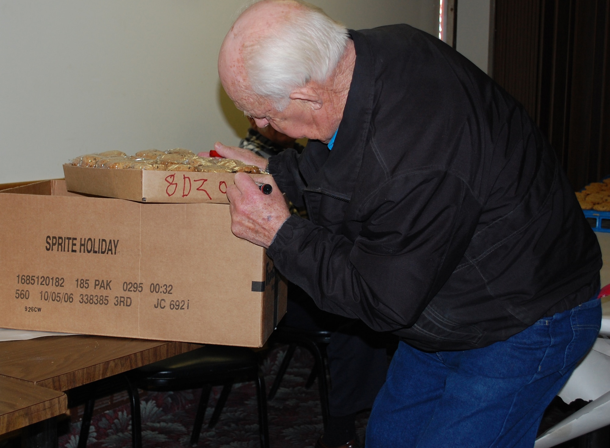 Montana Retiree Council member Bob Smith labels a box with how many cookies it contains and what kind they are Dec. 2. before adding them to the larger box. The larger containers later were taken to be stored until care packages were assembled Dec. 5. (U.S. Air Force photo/Valerie Mullett)