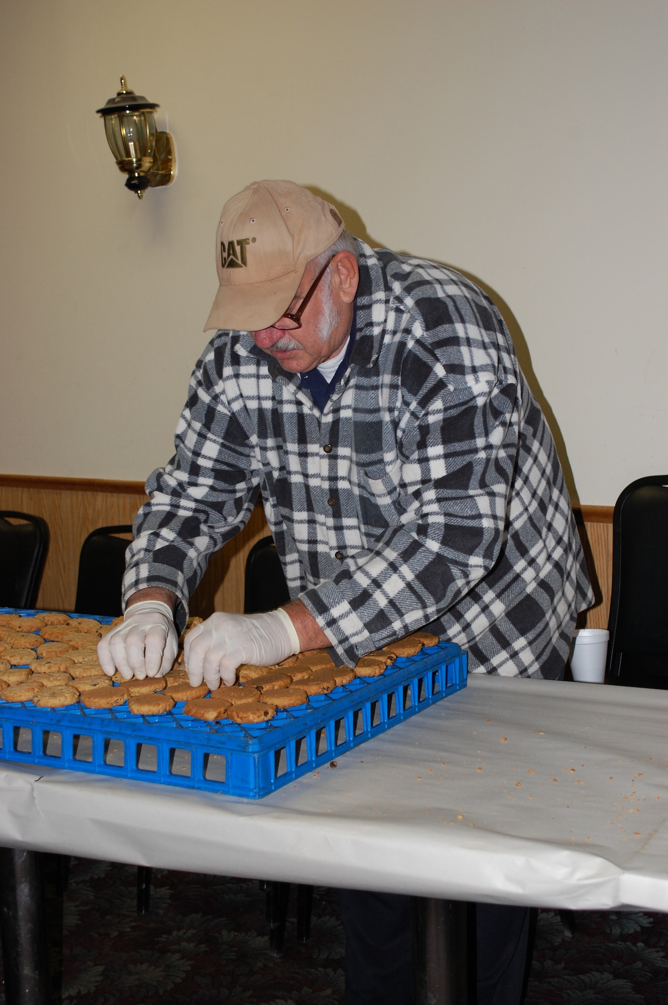 Volunteer Ken Croscutt turns cookies over on the cooling racks to speed the process along. After the cookies are cooled, more volunteers package bundles of cookies in saran wrap for later shipping overseas. (U.S. Air Force photo/Valerie Mullett)