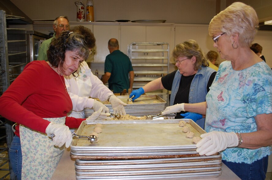 Clockwise from left, volunteers Lillian Howard, Dulce Spencer, Debbie Kissner and Della Johnson, scoop oatmeal raisin cookie dough onto baking pans Dec. 2 at the VFW Post 1087 kitchen. More than 1,600 dozen cookies were baked in three days to support Operation Happy Holidays. (U.S. Air Force photo/Valerie Mullett)