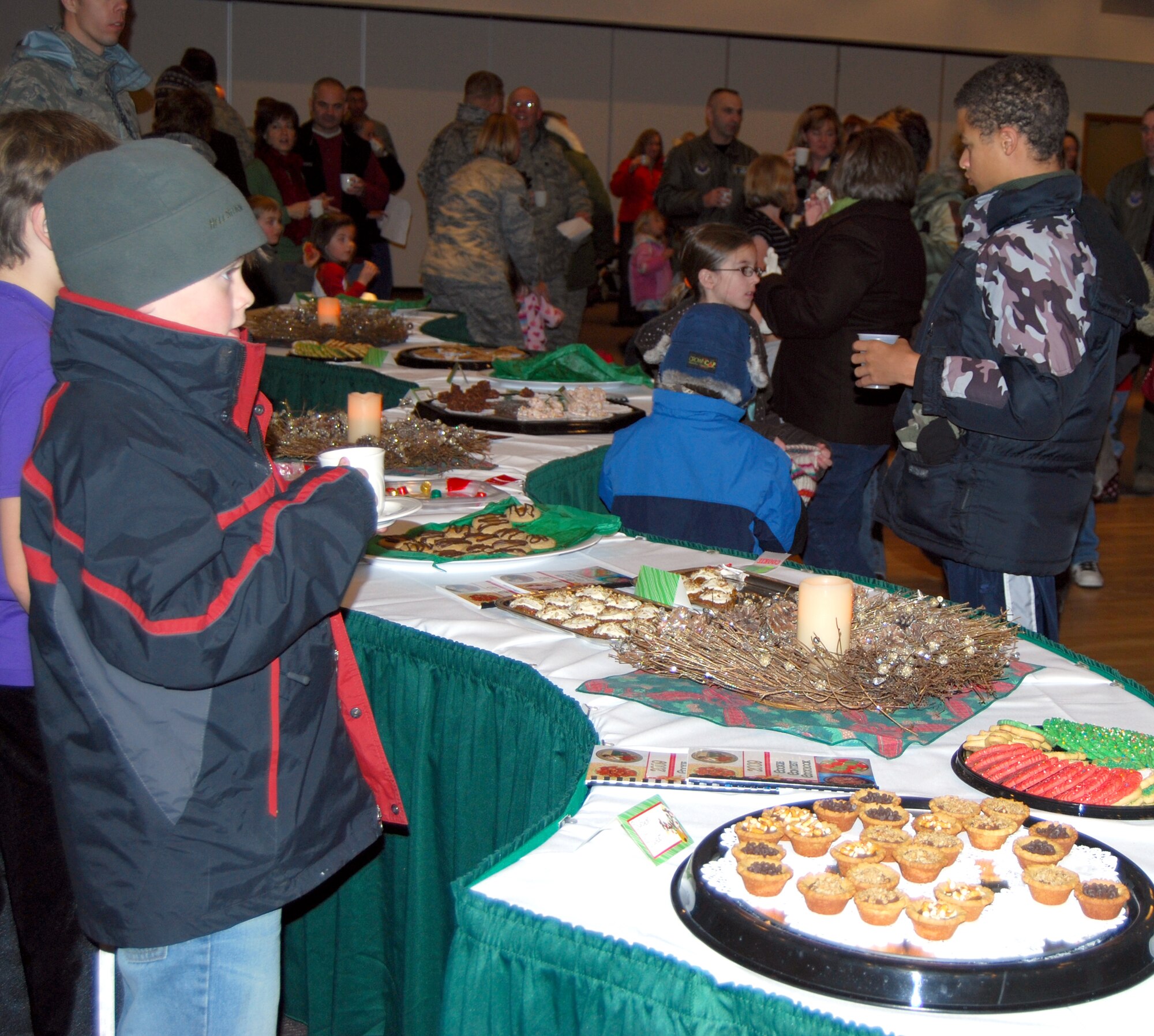 Airmen and their families enjoy hot cocoa and cookies after the Christmas tree lighting ceremony at the Grizzly Bend Club Dec. 3. The cookies were entries from the annual cookie contest. (U.S. Air Force photo/Airman 1st Class Kristina Overton)