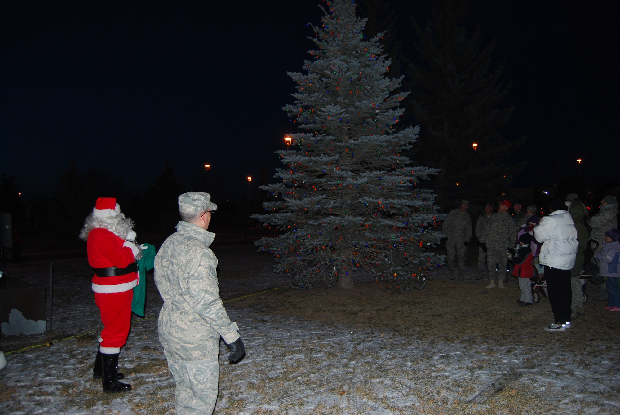 Col. Michael Fortney, 341st Missile Wing commander, Santa and more than 60 other Airmen and their families watched as the light-adorned Christmas tree outside the Grizzly Bend Club lit up at the annual tree lighting ceremony Dec. 3. Immediately following the tree lighting ceremony, everyone gathered in the Grizzly Bend Club ballroom to enjoy hot chocolate and cookies. (U.S. Air Force photo/Airman 1st Class Kristina Overton)