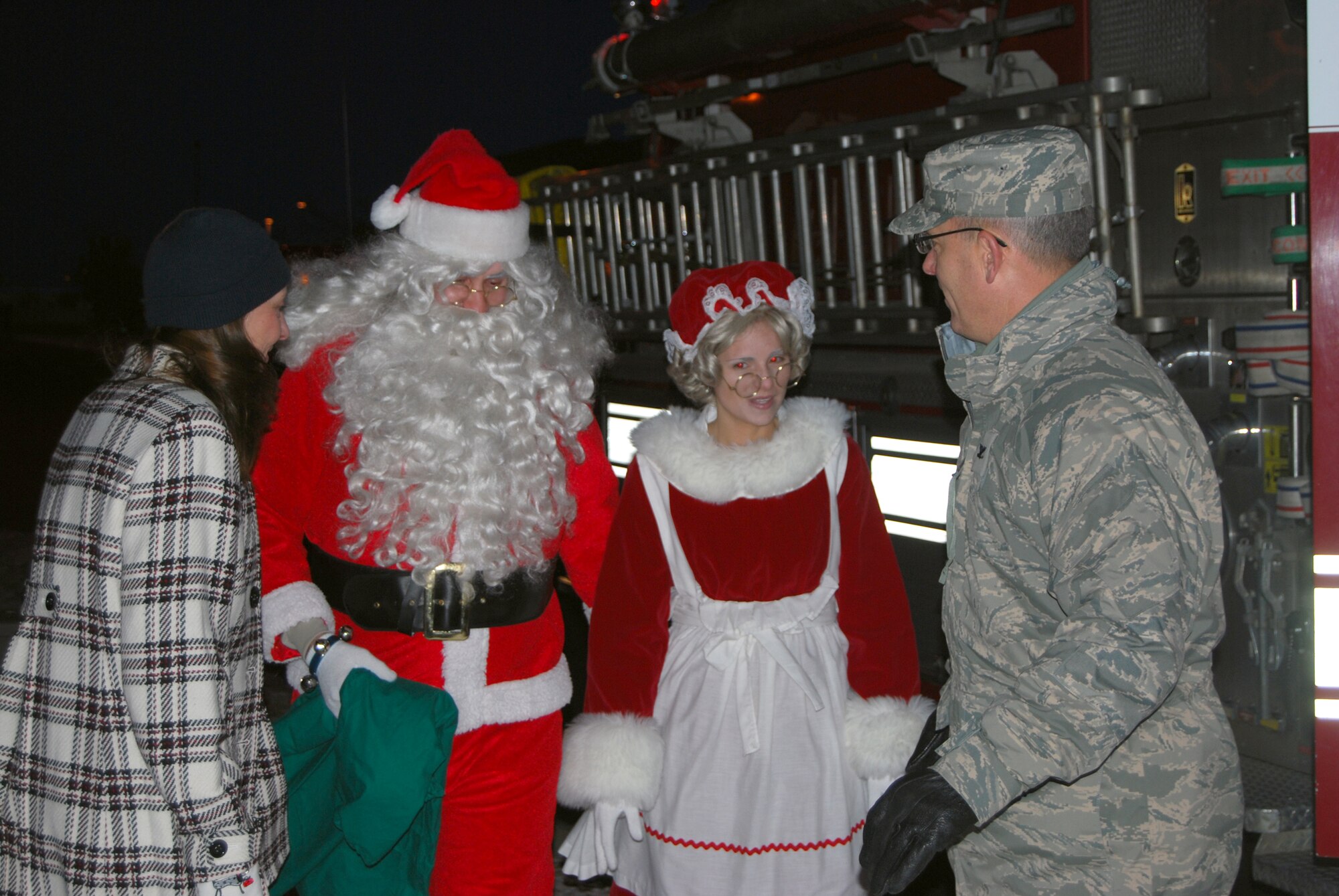 Col. Michael Fortney, 341st Missile Wing commander, and his wife, Karen, greet Santa and Mrs. Claus as they arrive by fire truck escort to the annual tree lighting ceremony Dec. 3. (U.S. Air Force photo/Airman 1st Class Kristina Overton)