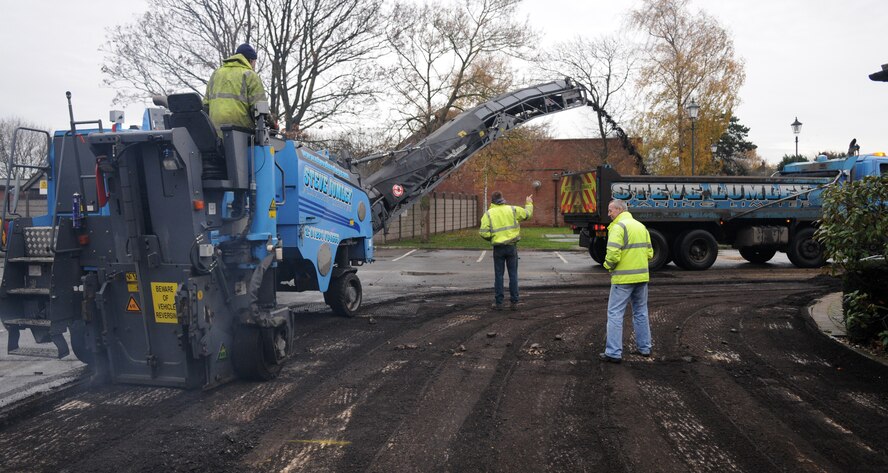 RAF MILDENHALL, England – Contractors remove asphalt from the access road leading into the auto hoppy shop Nov. 24. The weeklong process entailed scalping the surface, cleaning the area, applying fresh asphalt, and painting parking and road lines. (U.S. Air Force photo/ Staff Sgt. Jerry Fleshman)