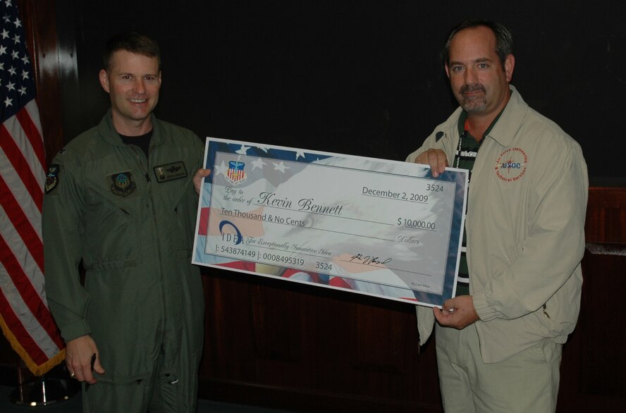 Col. Greg Lengyel, 1st Special Operations Wing commander, presents a $10,000 check to Kevin Bennett, an equipment specialist with the 1st Special Operations Maintenance Operations Squadron, at the 1st SOW Headquarters at Hurlburt Field Dec. 9. Mr. Bennett earned the check after submitting a cost-saving proposal to the Innovative Development through Employee Awareness Program. (Air Force photo by Airman 1st Class Joe McFadden)
