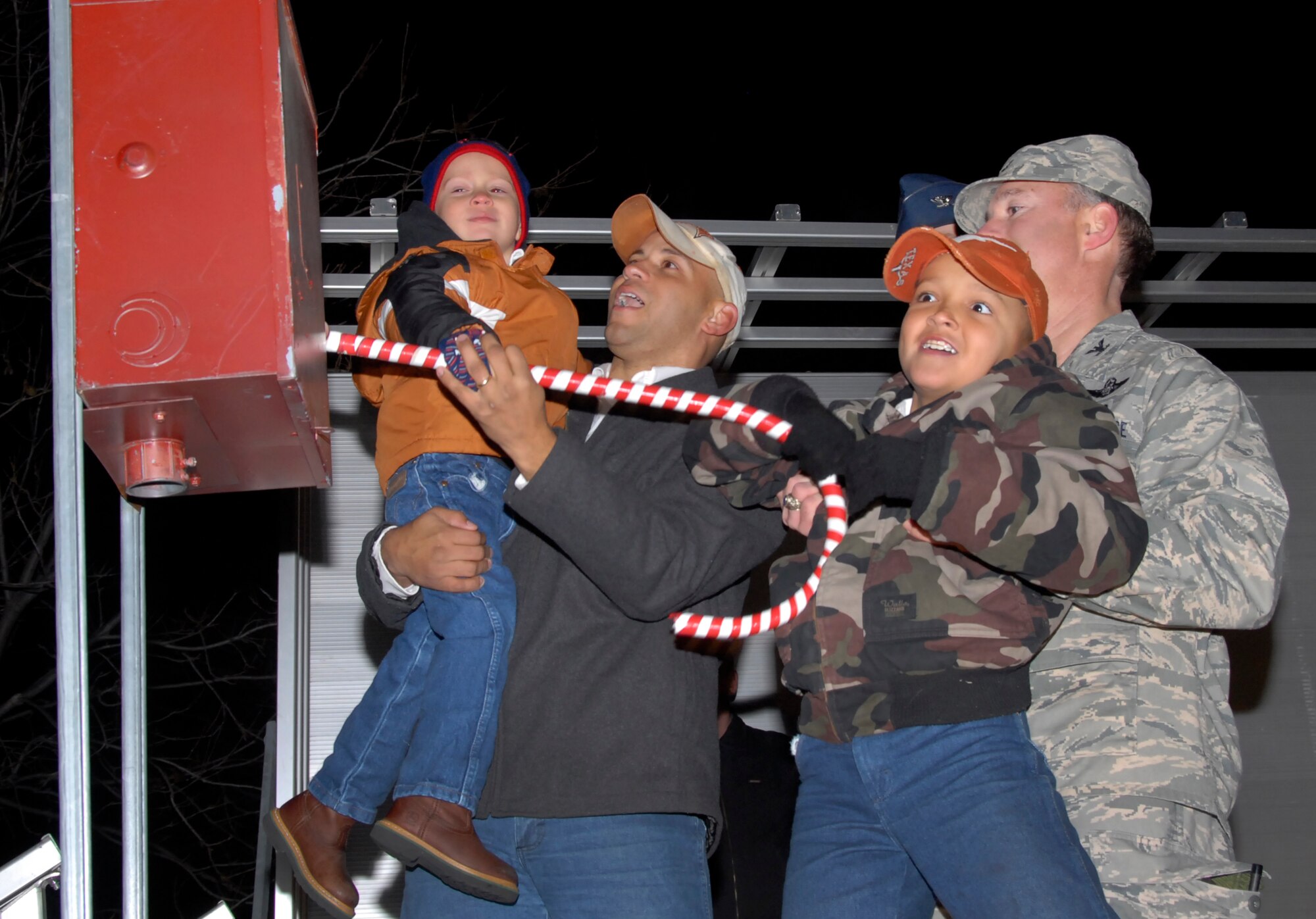 The Sheppard Family of the Year (from left to right), Kade, Staff Sgt. Philip Baham and Beaux, pull the official candy cane to light the base Holiday Tree with Col. Michael Hake (right), 82nd Training Wing vice commander, Dec. 7 at the Holiday Tree and Menorah Lighting at the corner of Avenue E and 1st Avenue. (U.S. Air Force photo/Harry Tonemah)