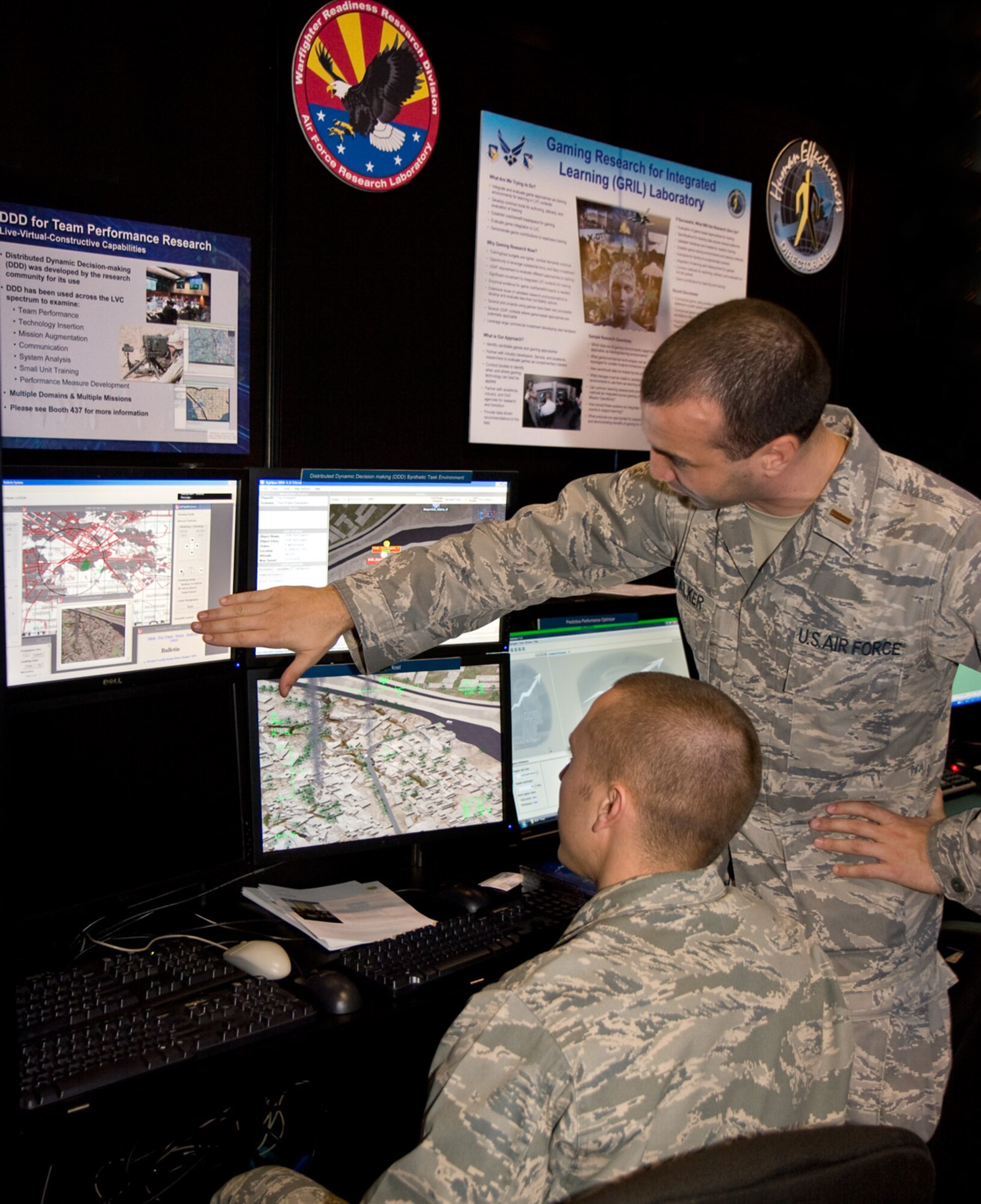 Second Lt. Shaun Sucillon (seated) and Second Lt. Joel Walker discuss a new gaming-based training capability at the Interservice/Industry Training, Simulation and Education Conference held Nov. 30 - Dec. 3 in Orlando, Florida. Researchers from the 711th Human Performance Wing, Human Effectiveness Directorate, Warfighter Readiness Research Division (711 HPW/RHA) are developing methods that quickly allow commercial game-based environments to be integrated and function seamlessly with each other and with RHA's Live-Virtual-Constructive training concept. (Photo by Gina Cinardo, 711 HPW)