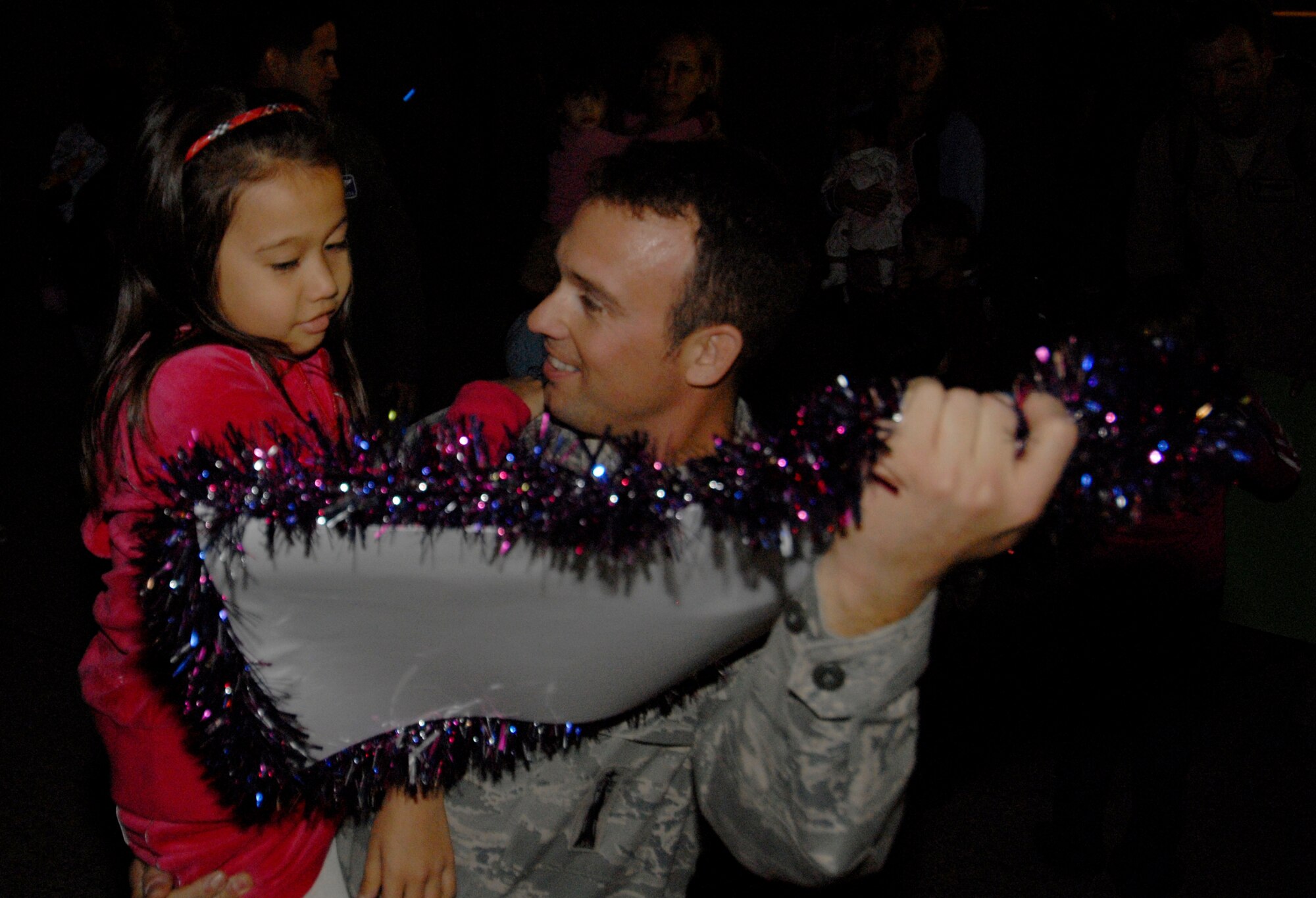 Tech. Sgt. Cory Kauffman, 18th Munitions Squadron, reads a welcome home sign from his daughter Bailey shortly after arriving outside Kadena's passenger terminal Dec. 8. Dozens of friends and family members welcomed more than 60 Airmen as they returned from a deployment to Afghanistan in support of Operation Enduring Freedom. (U.S. Air Force/Airman 1st Class Chad Warren)
