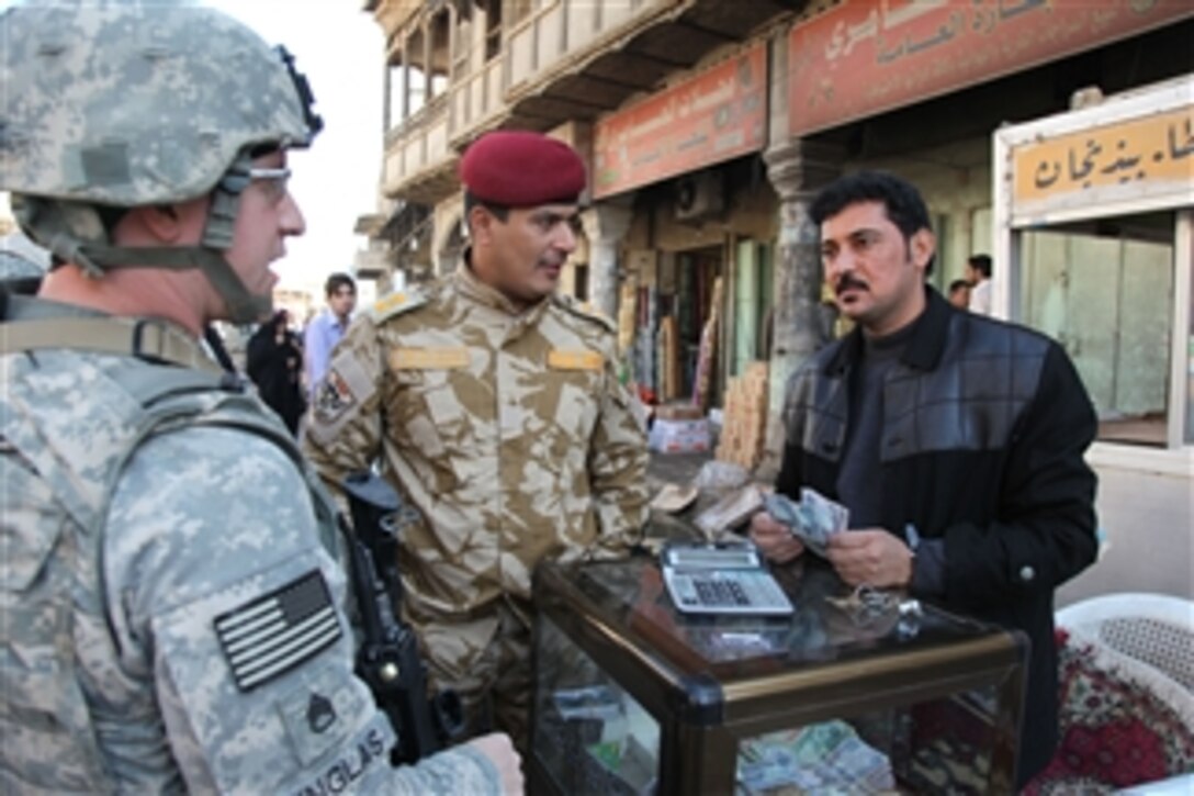 An Iraqi soldier, from the 14th Iraqi Division and U.S. Army Staff Sgt. Adam Vinglas attached to the Tactical Psychological Operations Detachment 3050th, 305th Psyop Company, 17th Fires Brigade, speak with a local cash exchange businessman about counterfeit money in the local community during a joint foot patrol in the Basra City Center, Basra, Iraq, on Dec. 3, 2009.  The patrol was conducted to get the local’s viewpoint on the Iranian influence.  