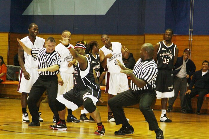 Officials Abe Roman (left) and Michael Westcott (right) along with Lade Majic (center) break out some of their best dance moves just before a foul shot during an exhibition game at the IronWorks Gym here Dec. 9. Throughout the game Majic was able to persuade many players and fans to break out in dance.