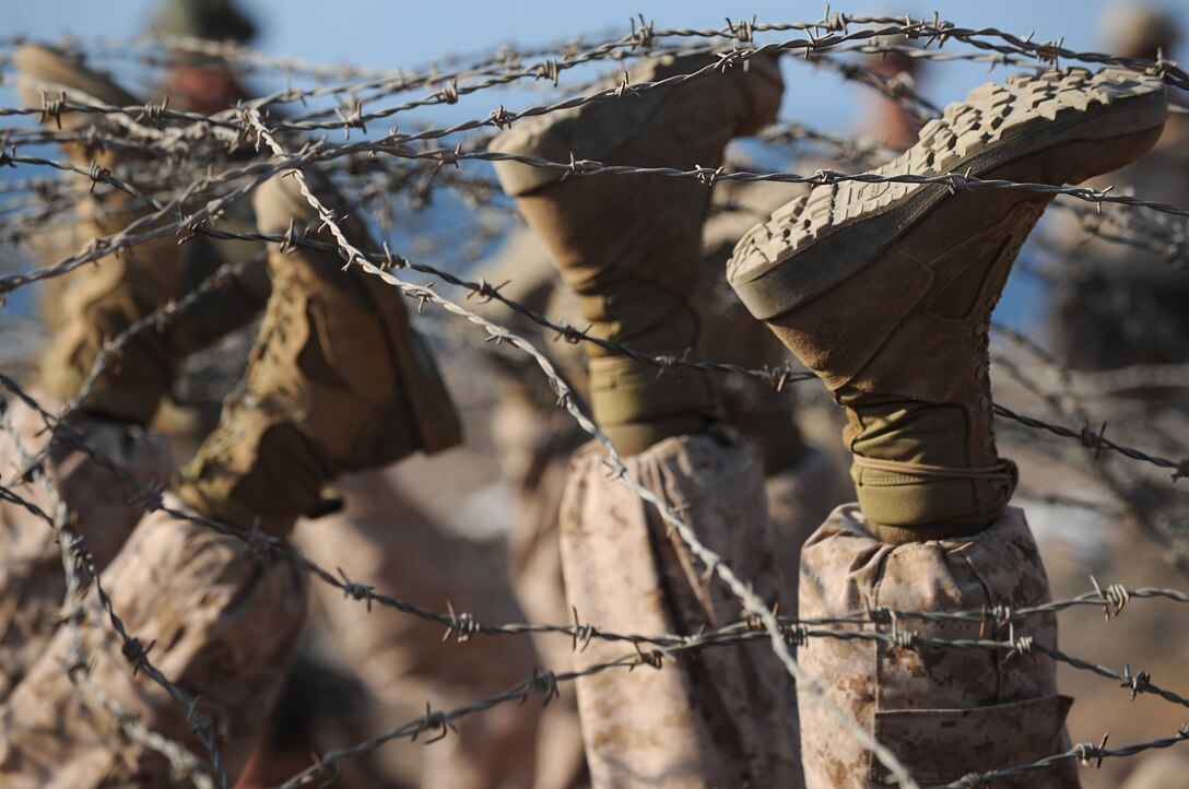 Marines with Company E, Battalion Landing Team 2/4, 11th Marine Expeditionary Unit, use their boots to lift barbed wire while running through an obstacle course at the Combat Training Center at Arta Beach here Dec. 9. The Marines trained with members of the 13th Demi-Brigade of the French Foreign Legion Dec. 4-10.