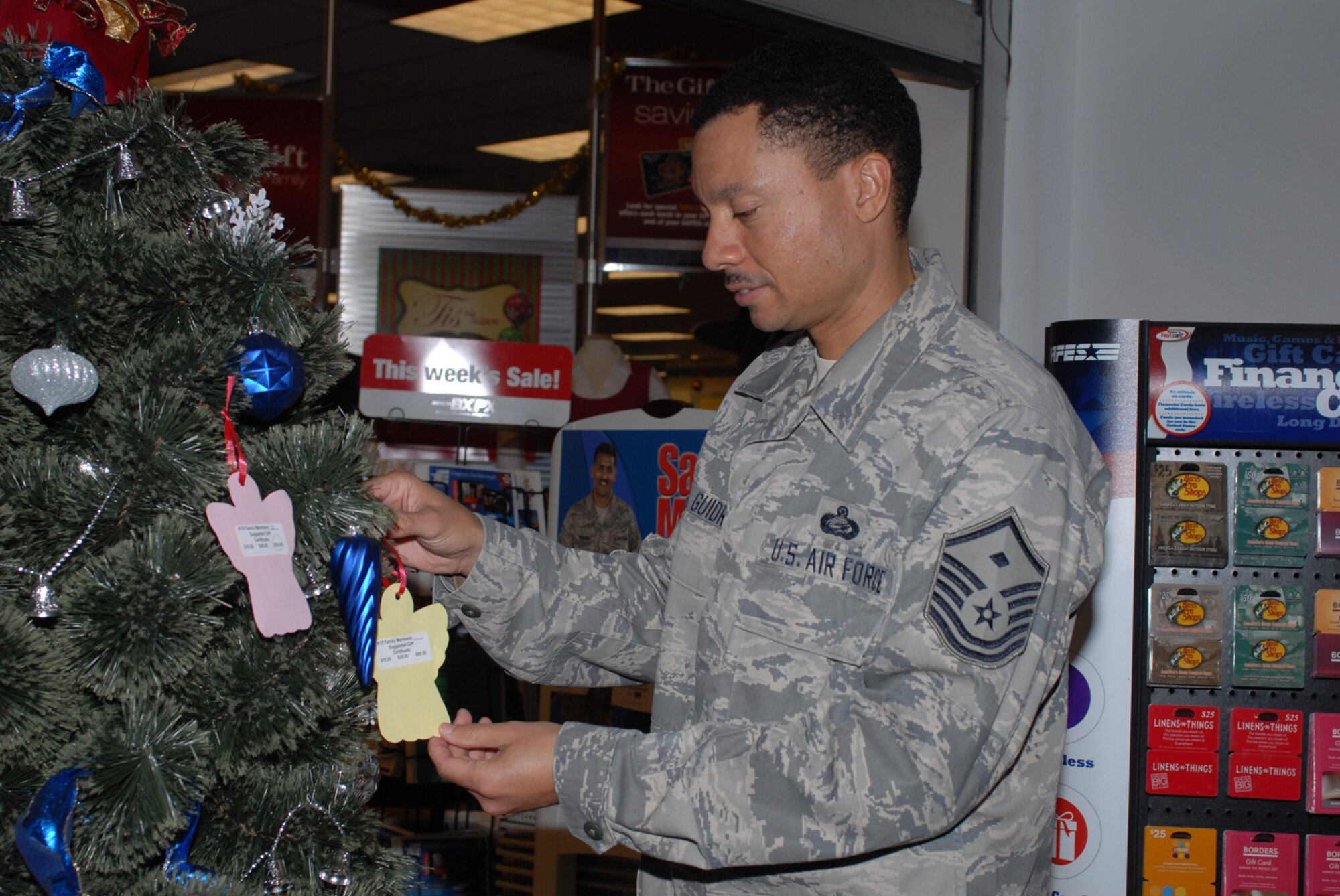 GOODFELLOW AIR FORCE BASE, Texas -- Master Sgt. John Guidry, 316th Training Squadron 1st Sgt., places an angel on the Christmas tree at the base exchange as part of Project Angel Tree, Dec. 8, 2009. The First Sergeants Council sponsors Project Angel Tree, an opportunity for Goodfellow members to assist others during the holiday season. The angels placed on the tree provide gift card suggestions for families needing assistance. (U.S. Air Force photo/Staff Sgt. Laura R. McFarlane)