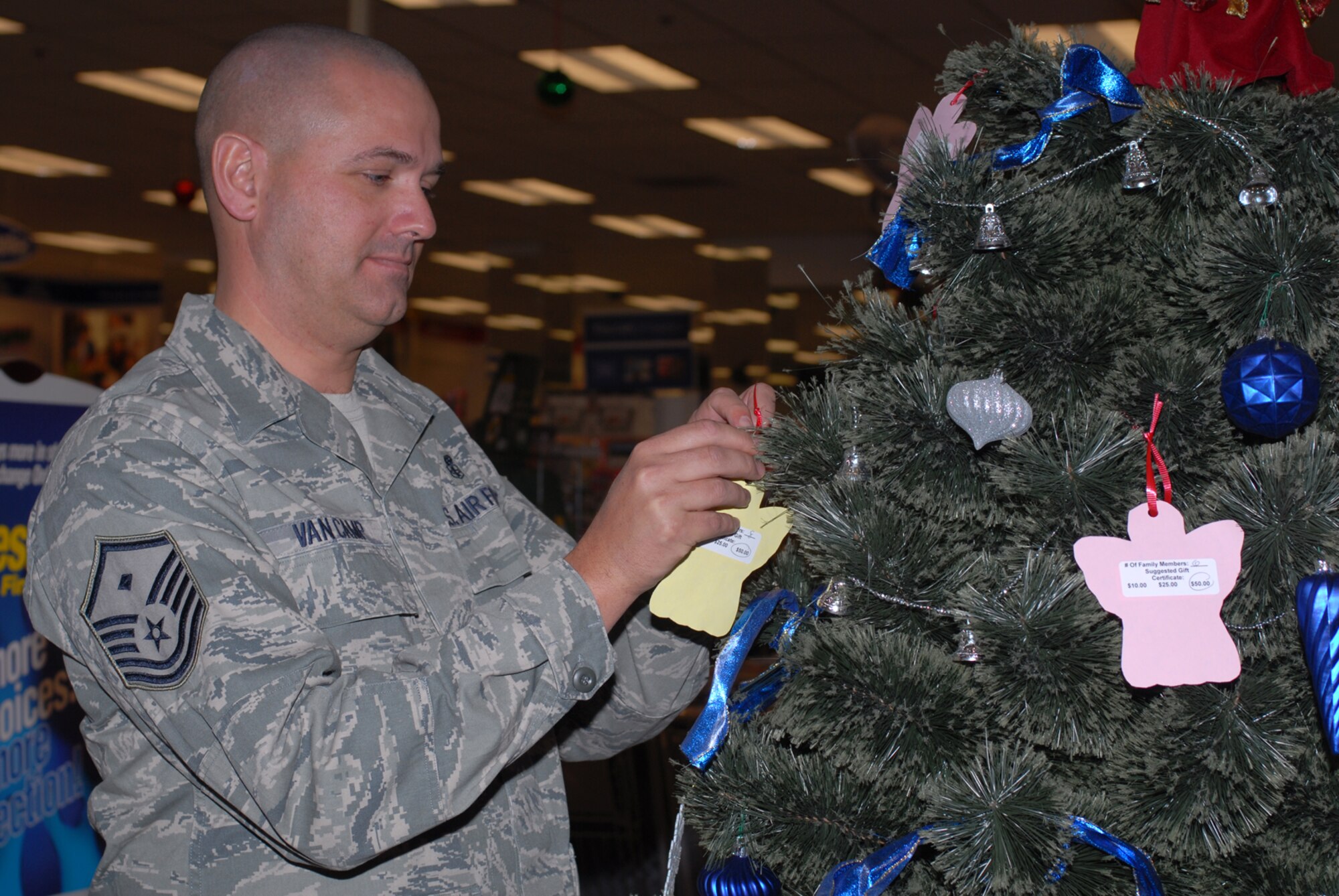 GOODFELLOW AIR FORCE BASE, Texas -- Master Sgt. Robert VanCamp, 17th Communications Squadron 1st Sgt., places an angel on the Christmas tree at the base exchange as part of Project Angel Tree, Dec. 8, 2009. The First Sergeants Council sponsors Project Angel Tree, an opportunity for Goodfellow members to assist others during the holiday season. The angels placed on the tree provide gift card suggestions for families needing assistance. (U.S. Air Force photo/Staff Sgt. Laura R. McFarlane)