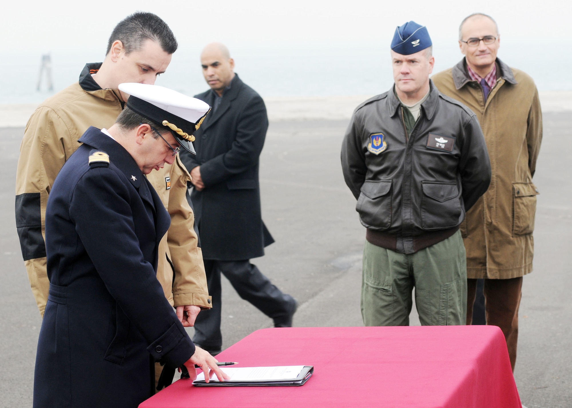 Col. Patrick Miller looks on as Italian Navy Cmdr. Franco Maltese signs a document transferring control of an aircraft wreckage to an Italian aero club during a ceremony Nov. 14, 2009, at the Chioggia Lagoon in Italy. Aeroclub Ferrarin in Thiene, Italy, will try to restore the wreckage, believed to be a World War II Army Air Force P-47 Thunderbolt fighter, recovered from the Adriatic Sea during a fishing expedition in May 2009. Colonel Miller is the 31st Operations Group commander from Aviano Air Base, Italy. (U.S. Air Force photo/Airman LaVel D. Sterling)