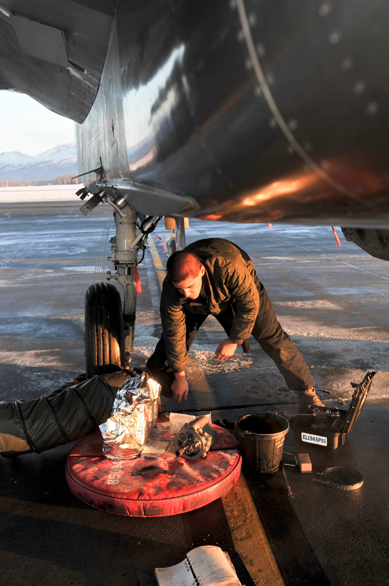 ELMENDORF AIR FORCE BASE, Alaska – Senior Airman Matthew Orozco, 19th Aircraft Maintenance Unit crew chief, works on replacing a seal in the underside of an Elmendorf F-15 Eagle Dec. 7. Orozco said that one of the biggest challenges of doing his job in the arctic environment is working with cold hands on freezing metal. (U.S. Air Force photo/Airman 1st Class Christopher Gross)
