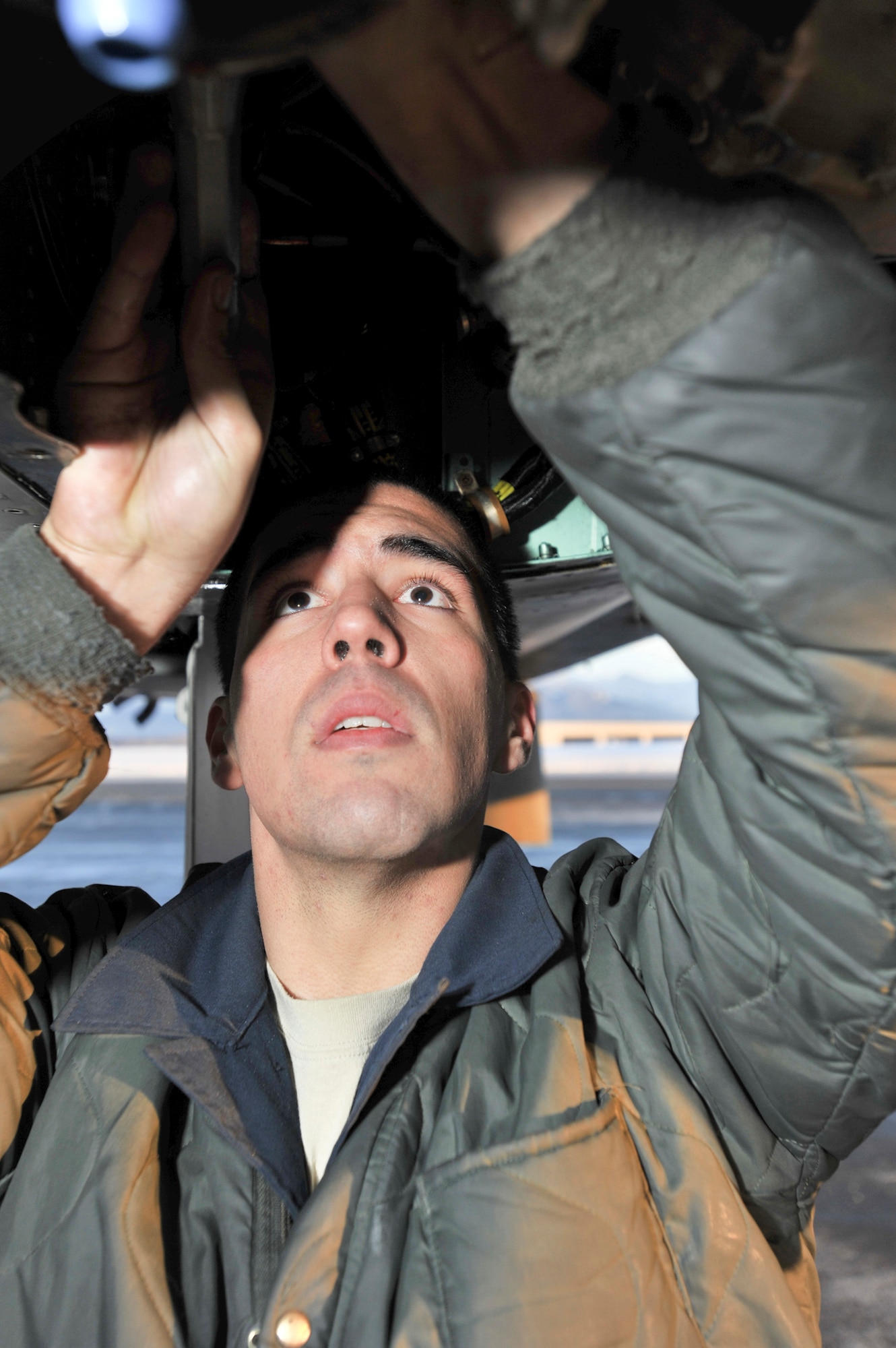 ELMENDORF AIR FORCE BASE, Alaska – Senior Airman Matthew Orozco, 19th Aircraft Maintenance Unit crew chief, looks up into the underside of an Elmendorf F-15 Eagles Dec. 7. Orozco said there’s more seal and wire damage to aircraft in the winter months.  (U.S. Air Force photo/Airman 1st Class Christopher Gross)